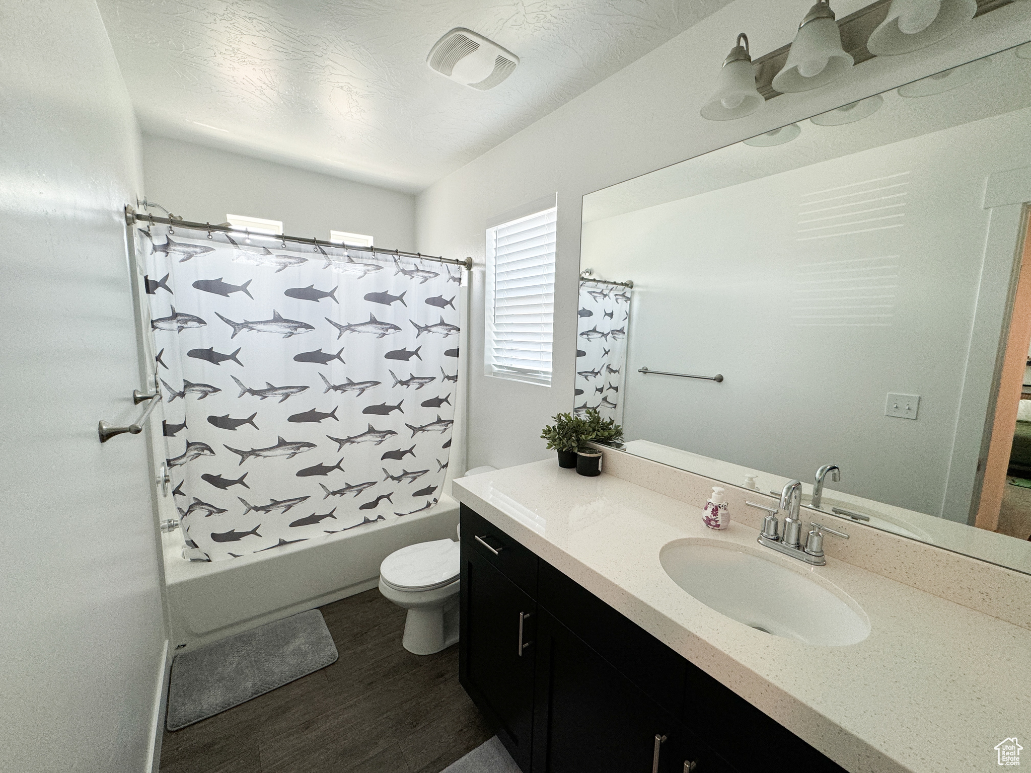 Full bathroom featuring wood-type flooring, shower / bath combo, vanity, and toilet