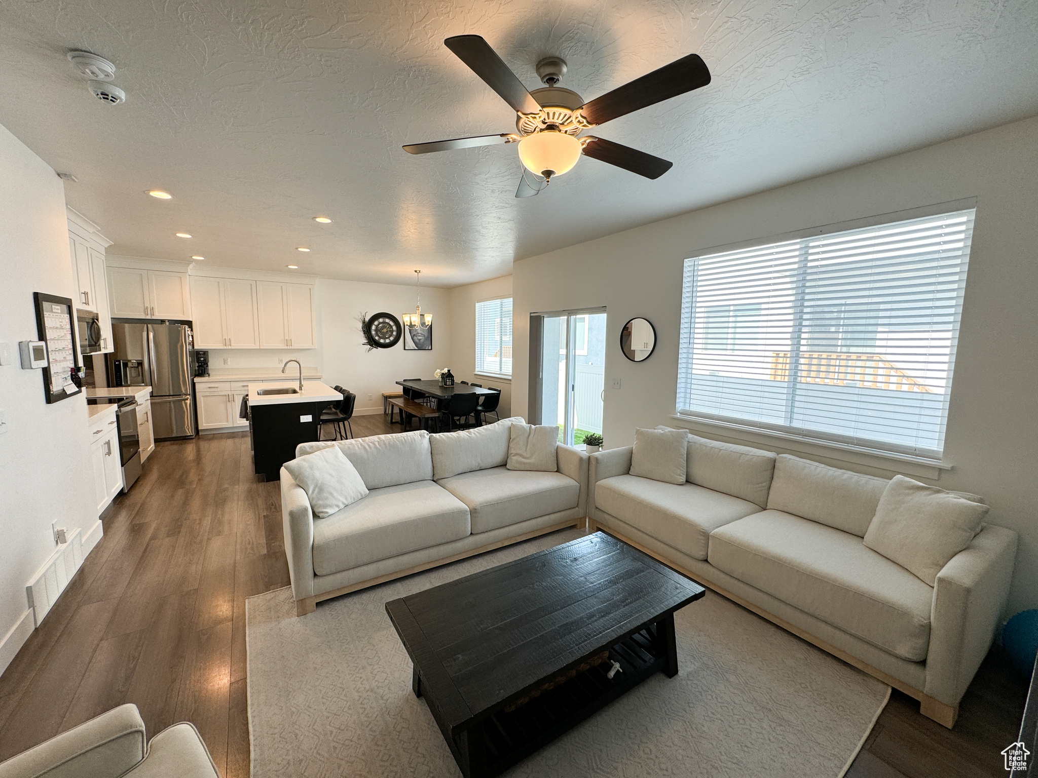 Living room featuring ceiling fan with notable chandelier, a textured ceiling, hardwood / wood-style floors, and sink