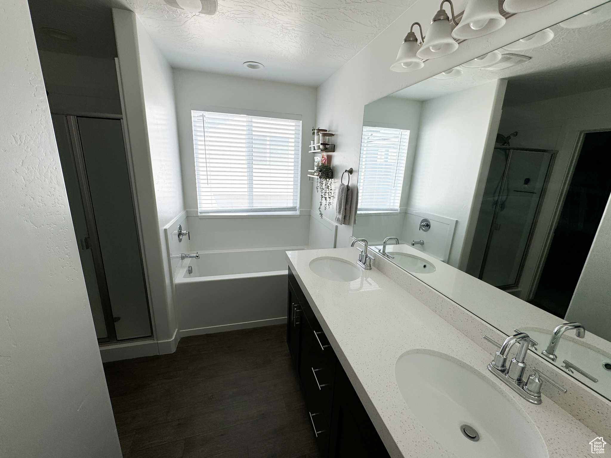 Bathroom with a textured ceiling, independent shower and bath, vanity, and hardwood / wood-style flooring