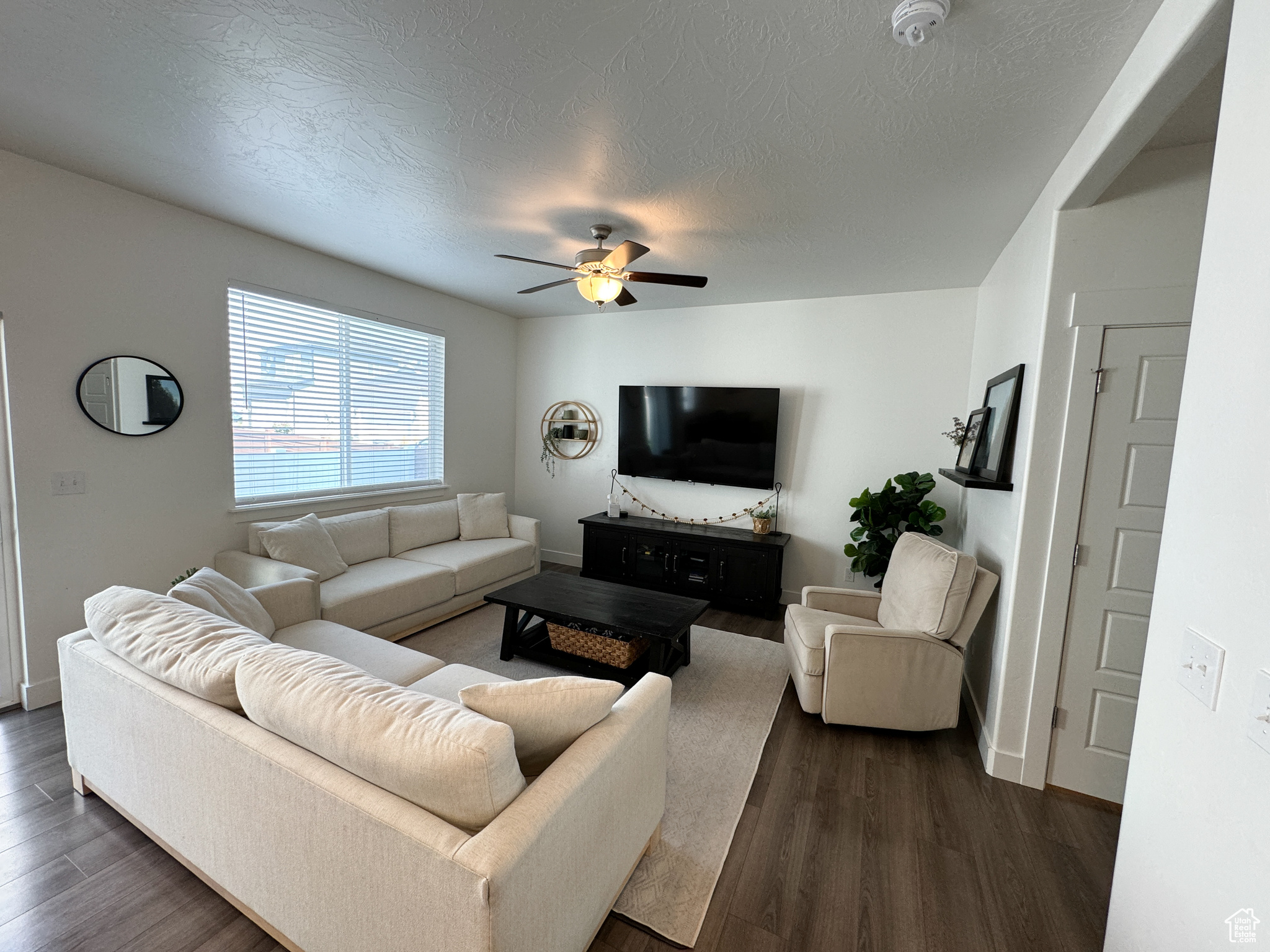 Living room with ceiling fan, dark hardwood / wood-style floors, and a textured ceiling