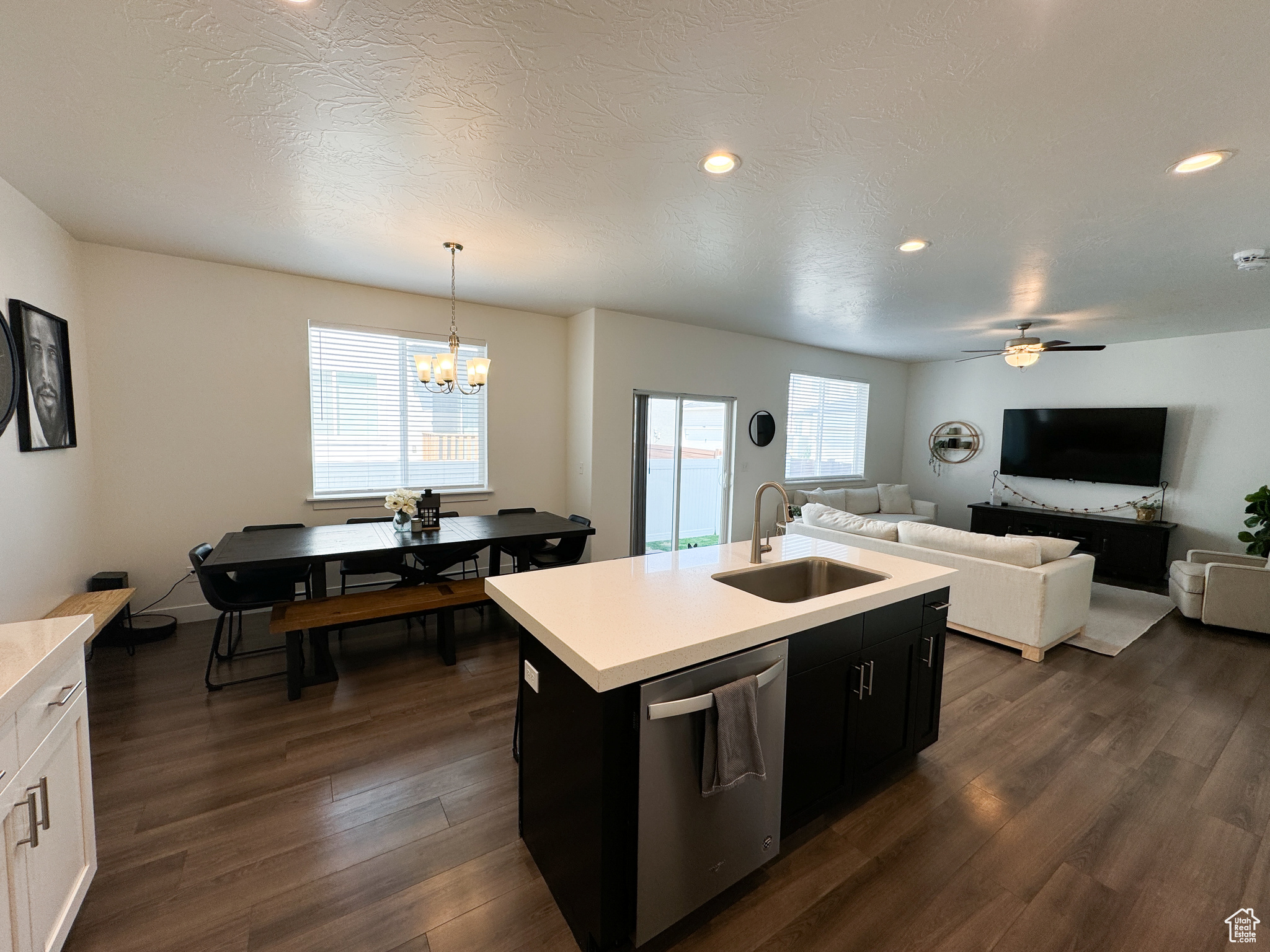 Kitchen with stainless steel dishwasher, a kitchen island with sink, pendant lighting, and plenty of natural light