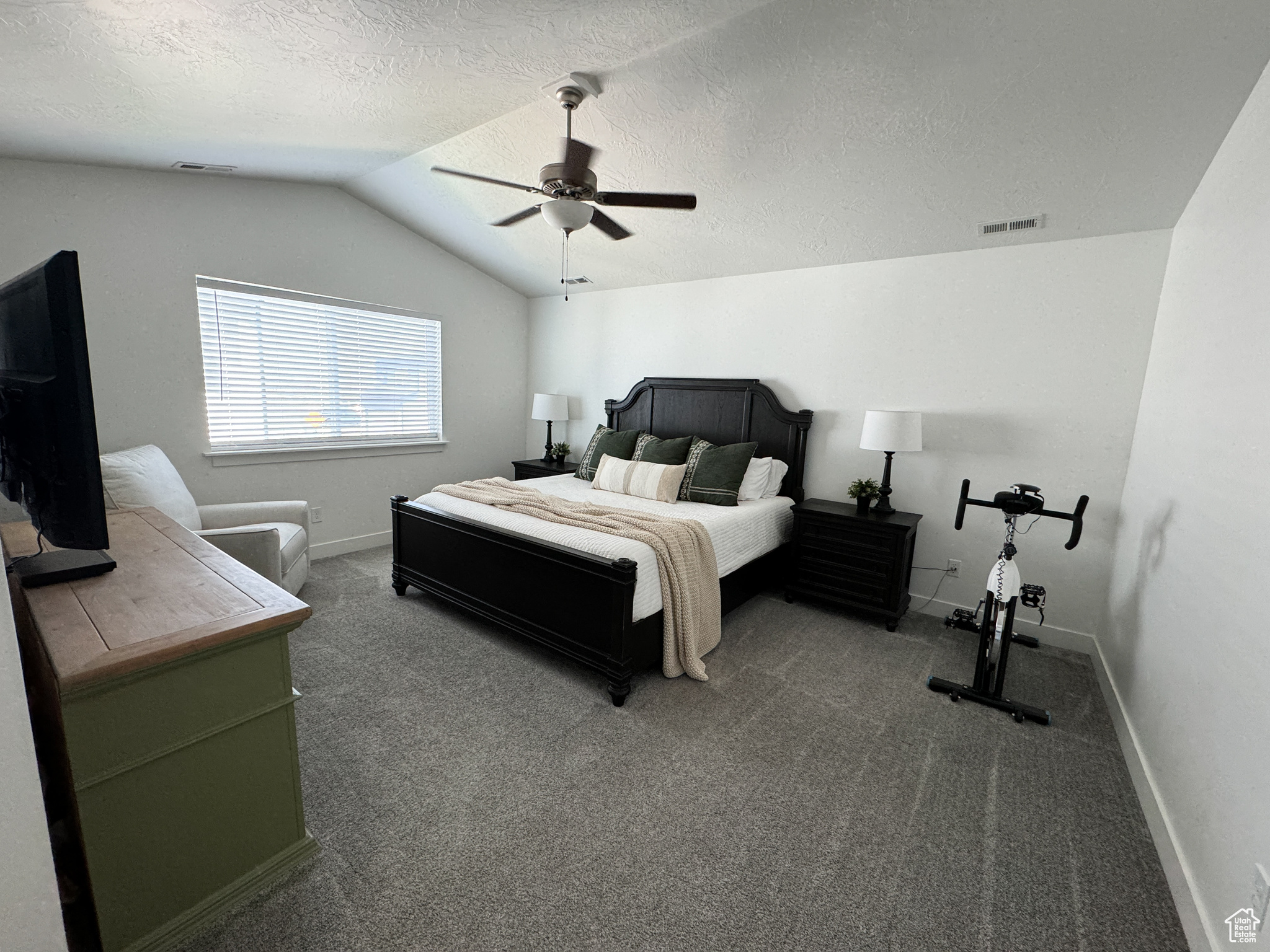 Bedroom featuring carpet, lofted ceiling, ceiling fan, and a textured ceiling