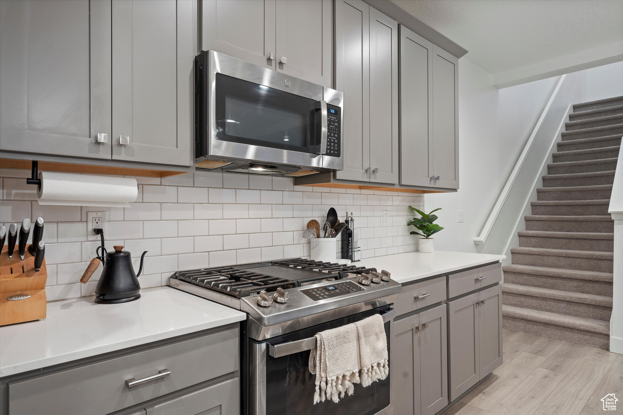 Kitchen featuring gray cabinets, light hardwood / wood-style flooring, stainless steel appliances, and tasteful backsplash