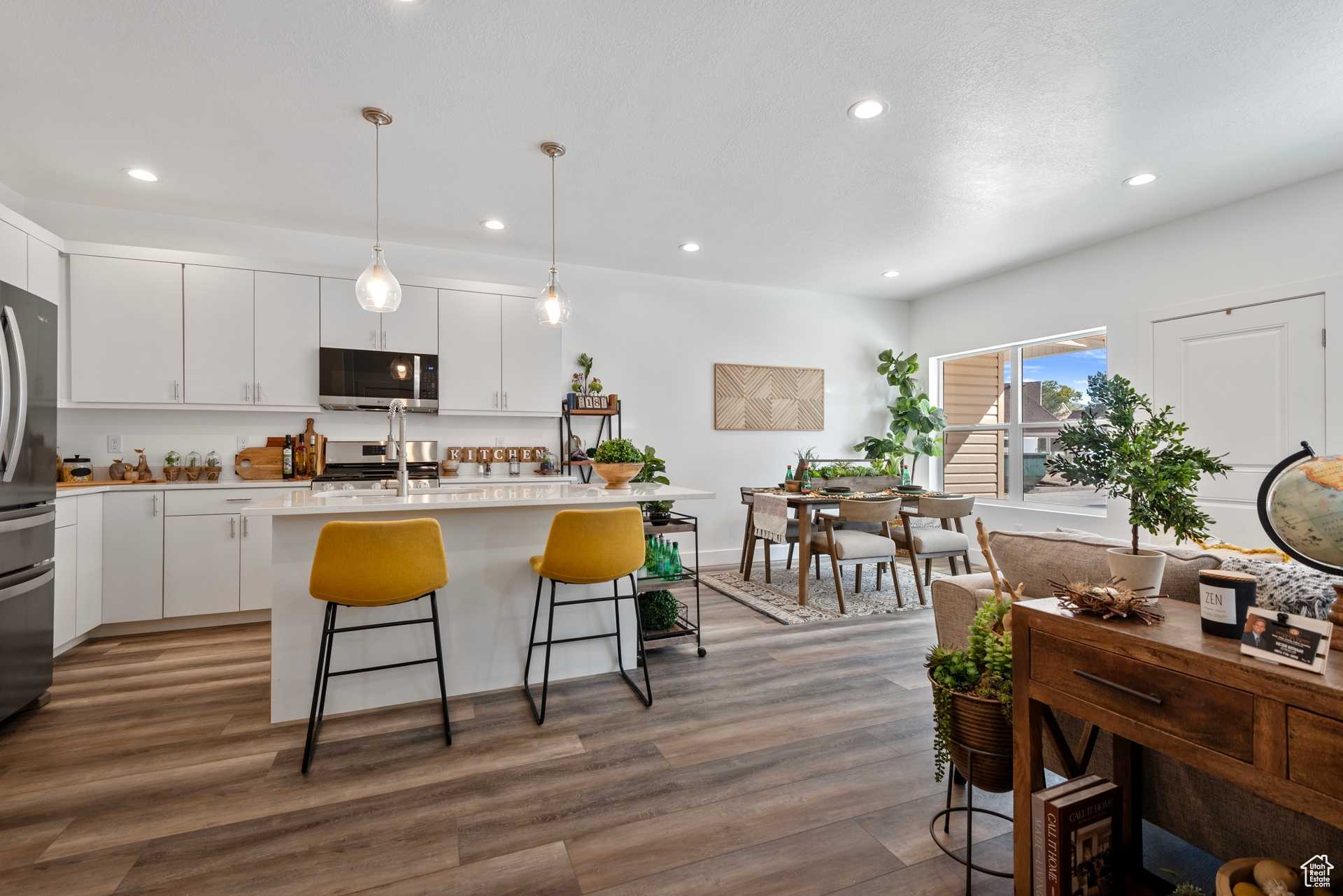 Kitchen with pendant lighting, stainless steel appliances, white cabinets, and dark hardwood / wood-style flooring