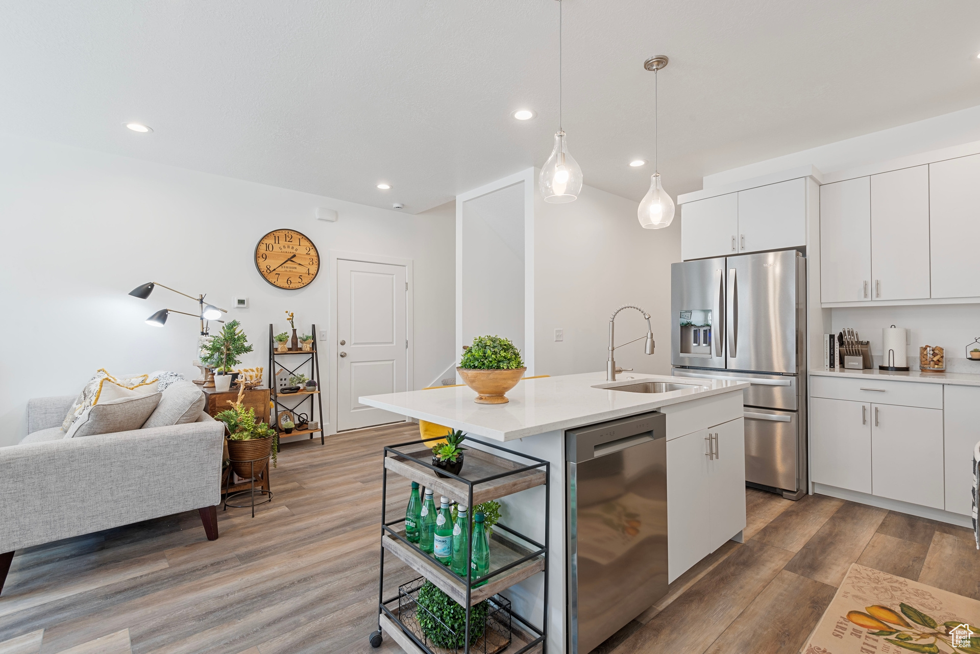 Kitchen with a kitchen island with sink, sink, white cabinetry, stainless steel appliances, and hardwood / wood-style floors