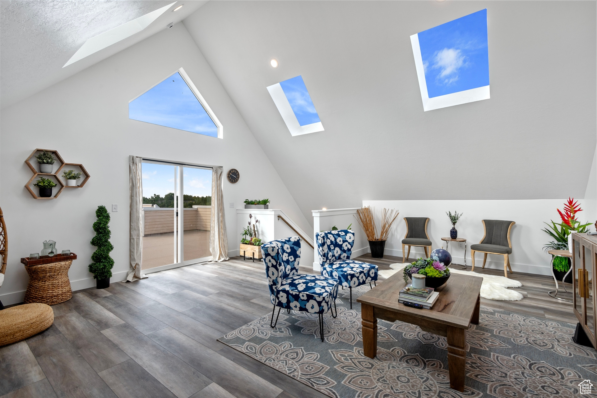 Living room featuring a skylight, a textured ceiling, high vaulted ceiling, and hardwood / wood-style flooring