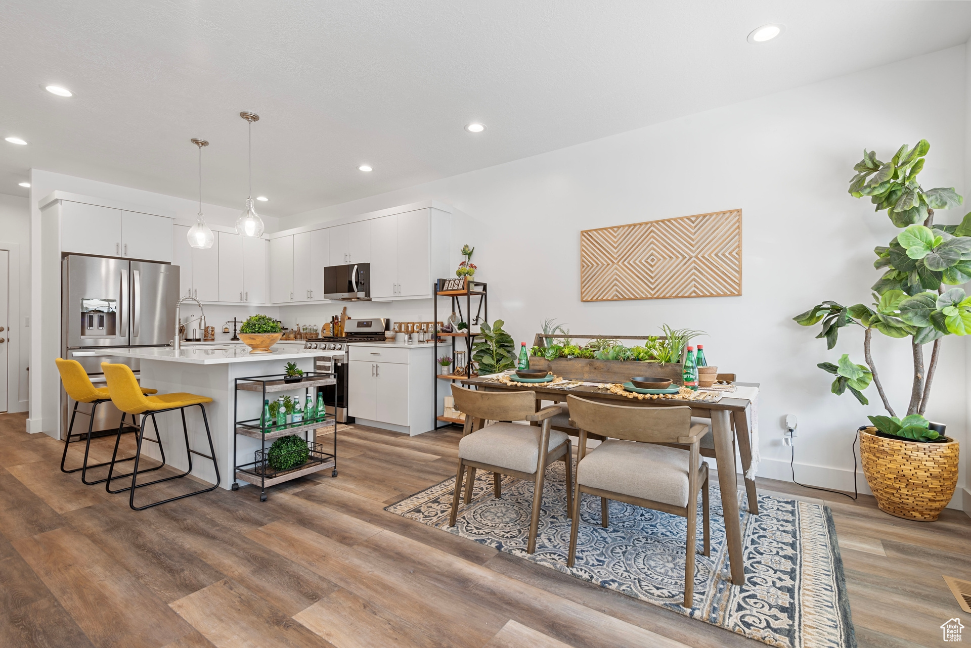 Kitchen featuring light hardwood / wood-style flooring, pendant lighting, stainless steel appliances, and white cabinets