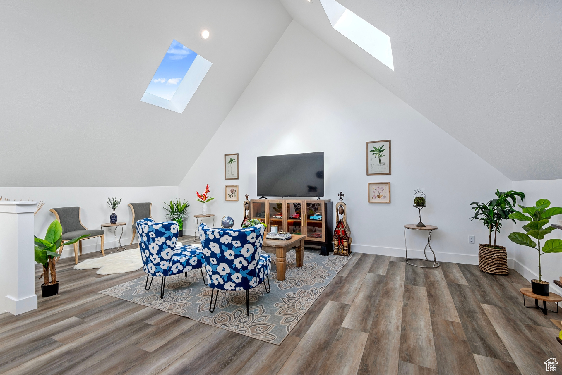 Living room with a skylight, high vaulted ceiling, and hardwood / wood-style flooring