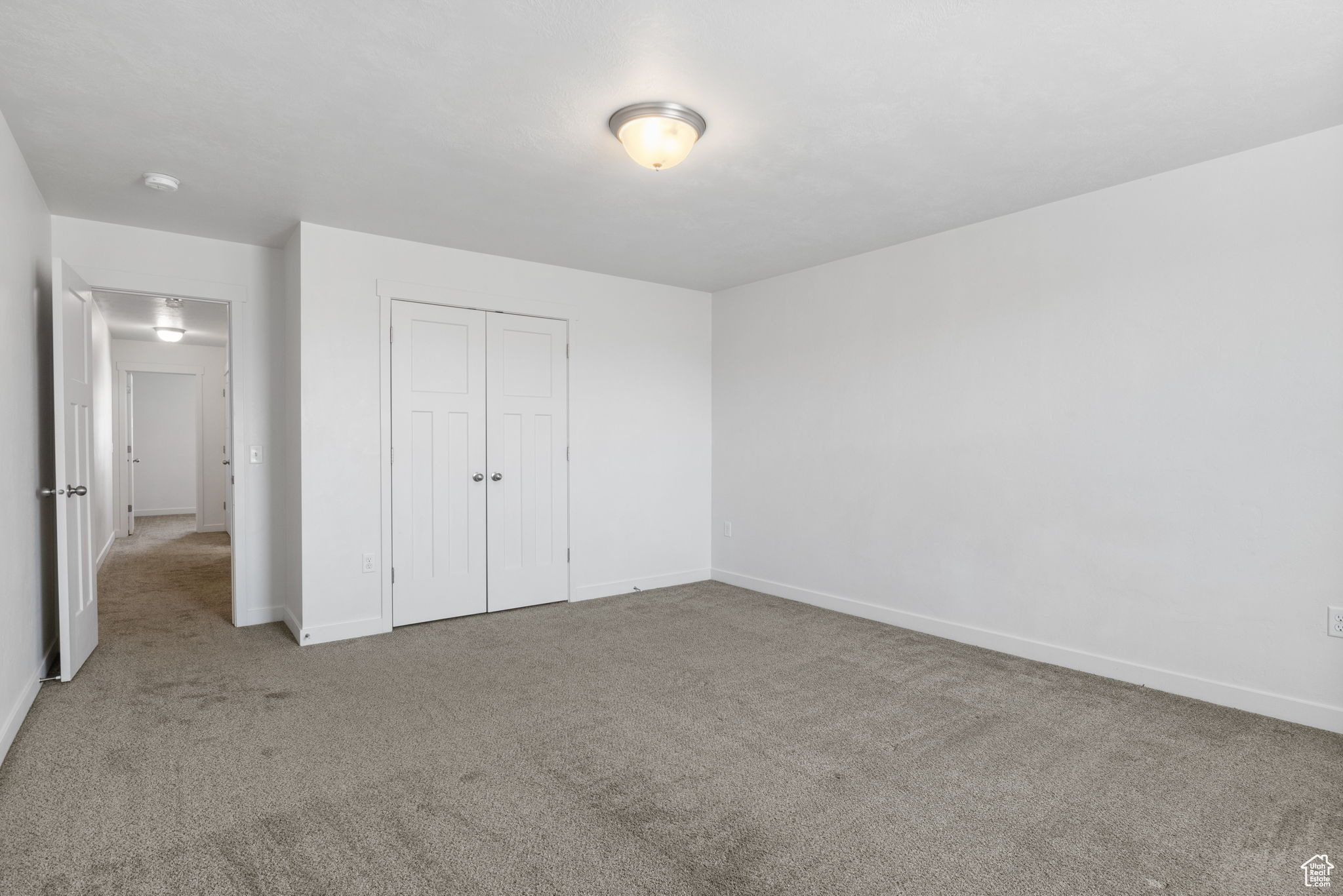 Unfurnished bedroom featuring light carpet and a closet