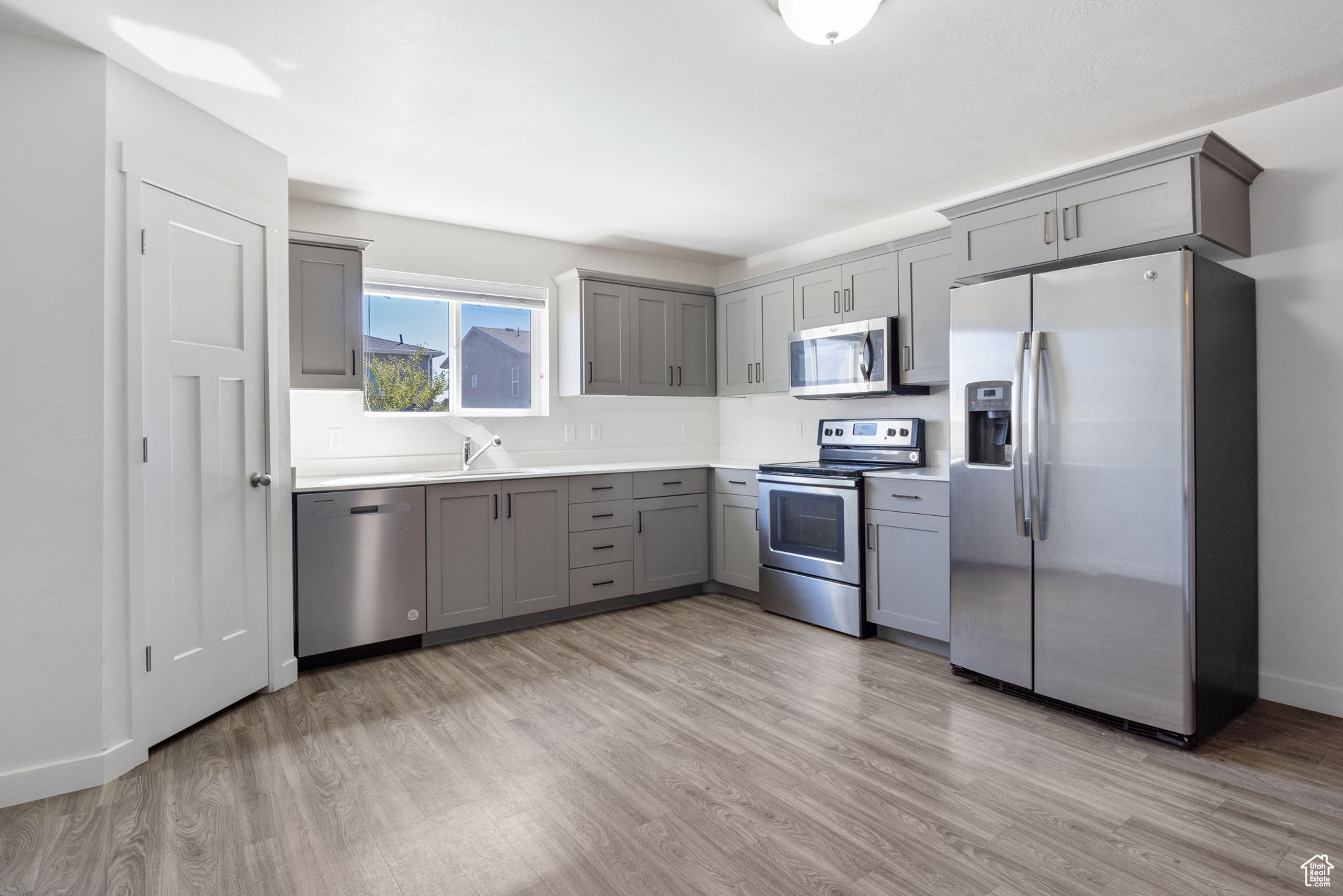 Kitchen with stainless steel appliances, light wood-type flooring, and gray cabinetry