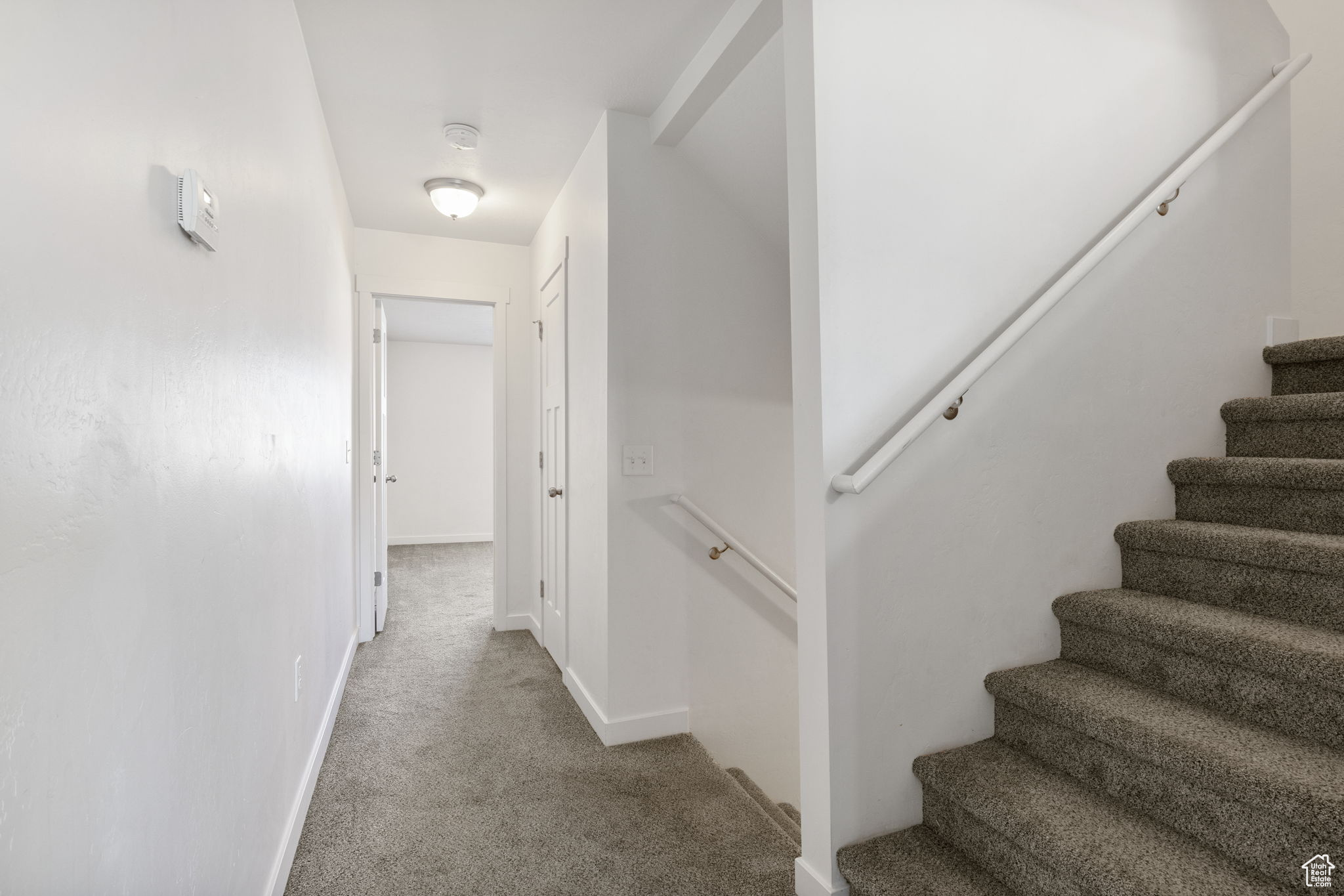 Corridor featuring light colored carpet