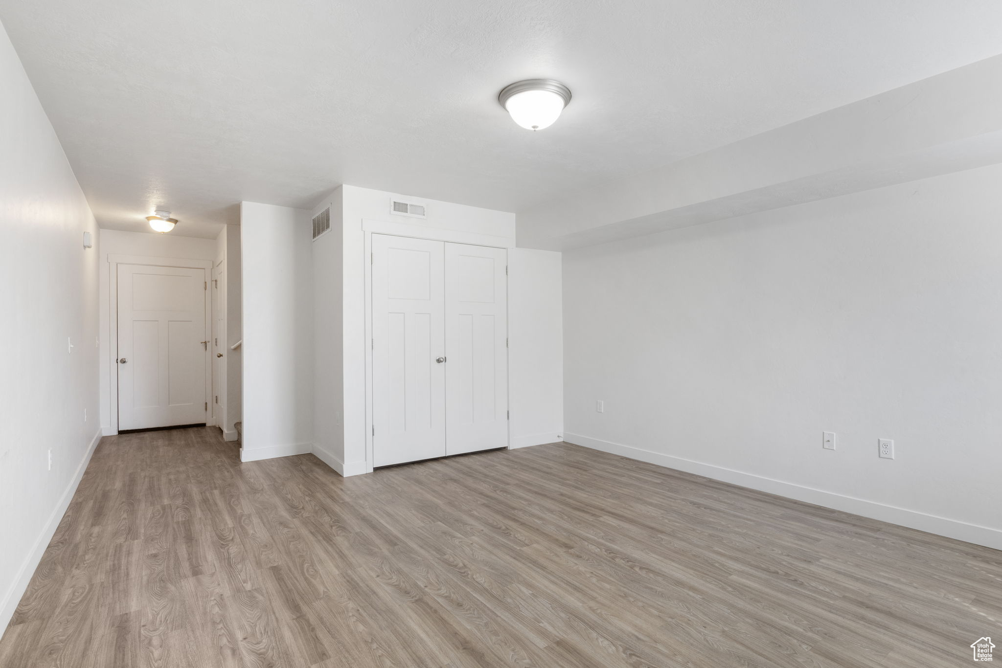 Unfurnished bedroom with light hardwood / wood-style floors and a closet