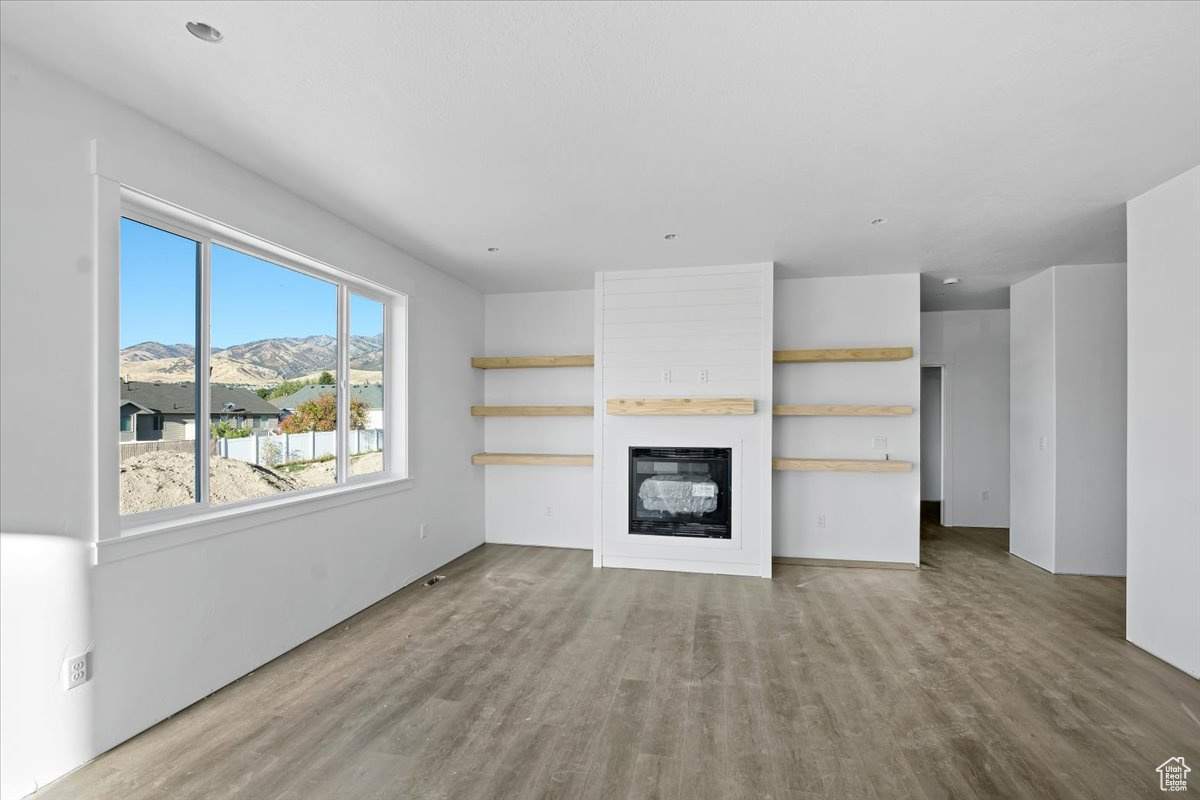 Unfurnished living room featuring a mountain view, light hardwood / wood-style floors, and a fireplace