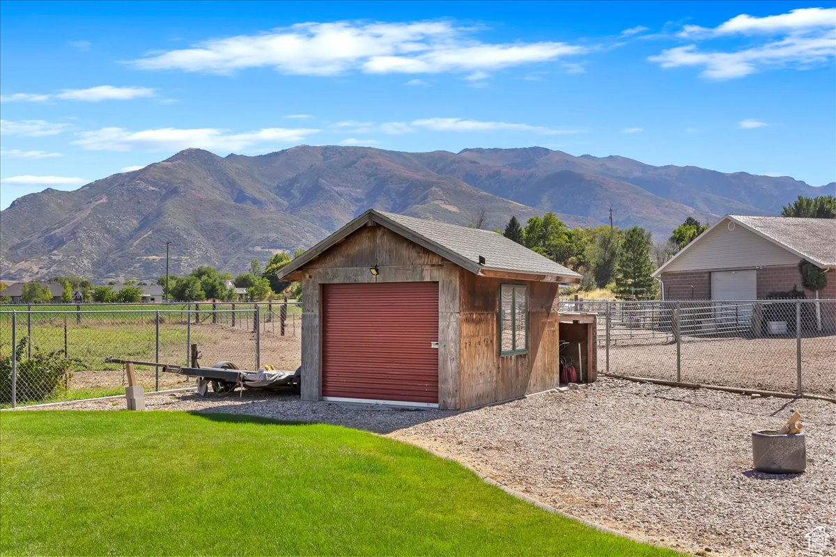 View of front of house with a mountain view, a rural view, a front lawn, and a storage unit