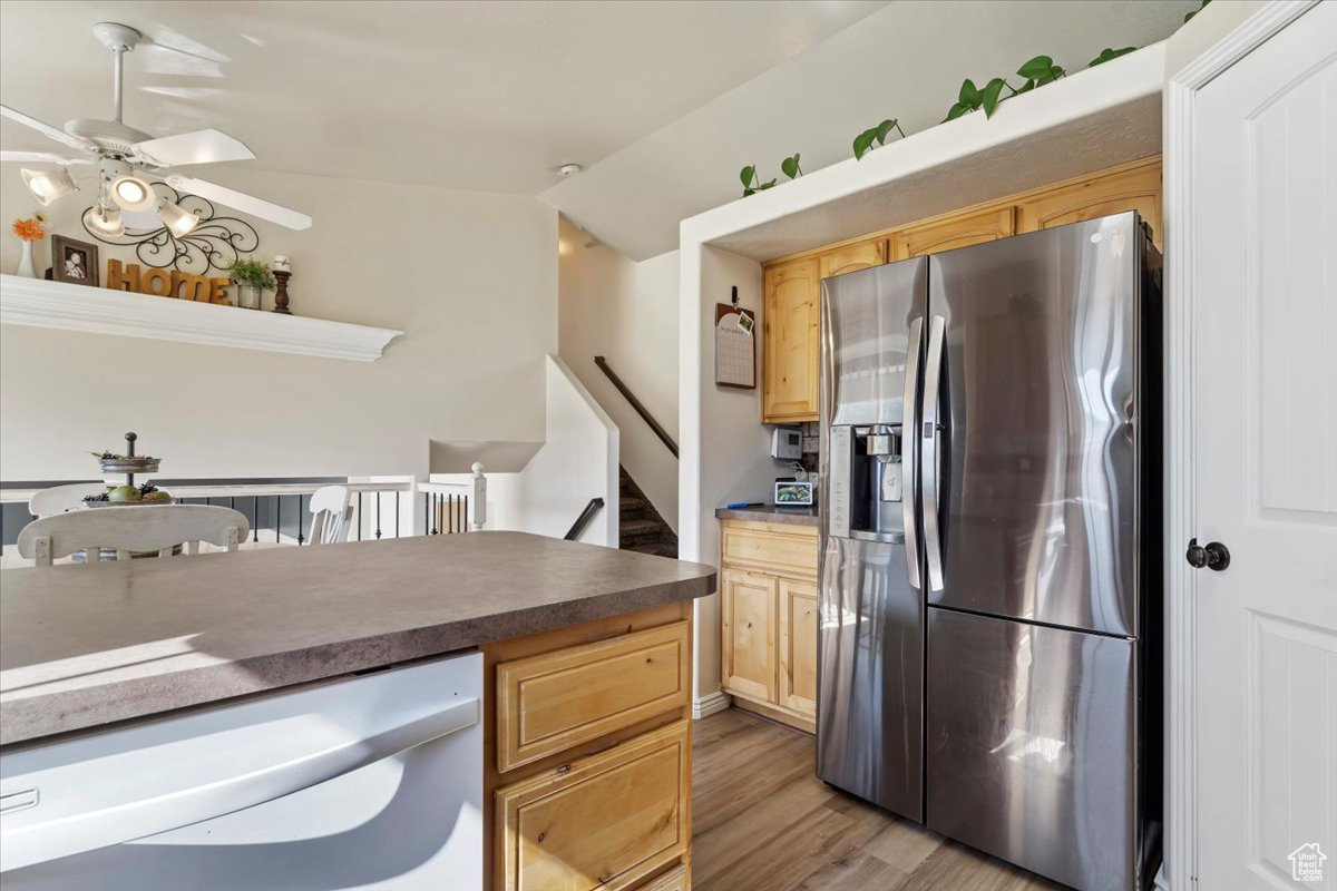 Kitchen with vaulted ceiling, light hardwood / wood-style flooring, white dishwasher, ceiling fan, and stainless steel fridge