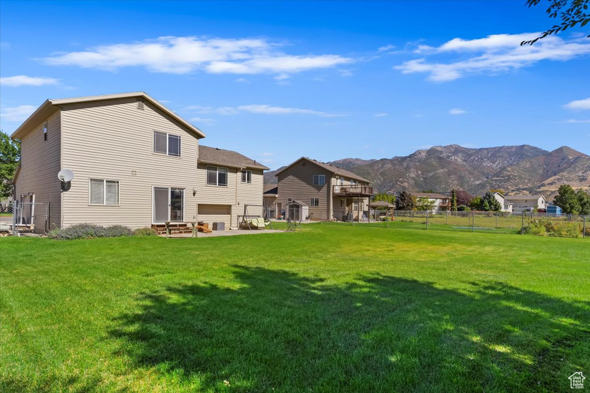 Rear view of house featuring a mountain view and a yard