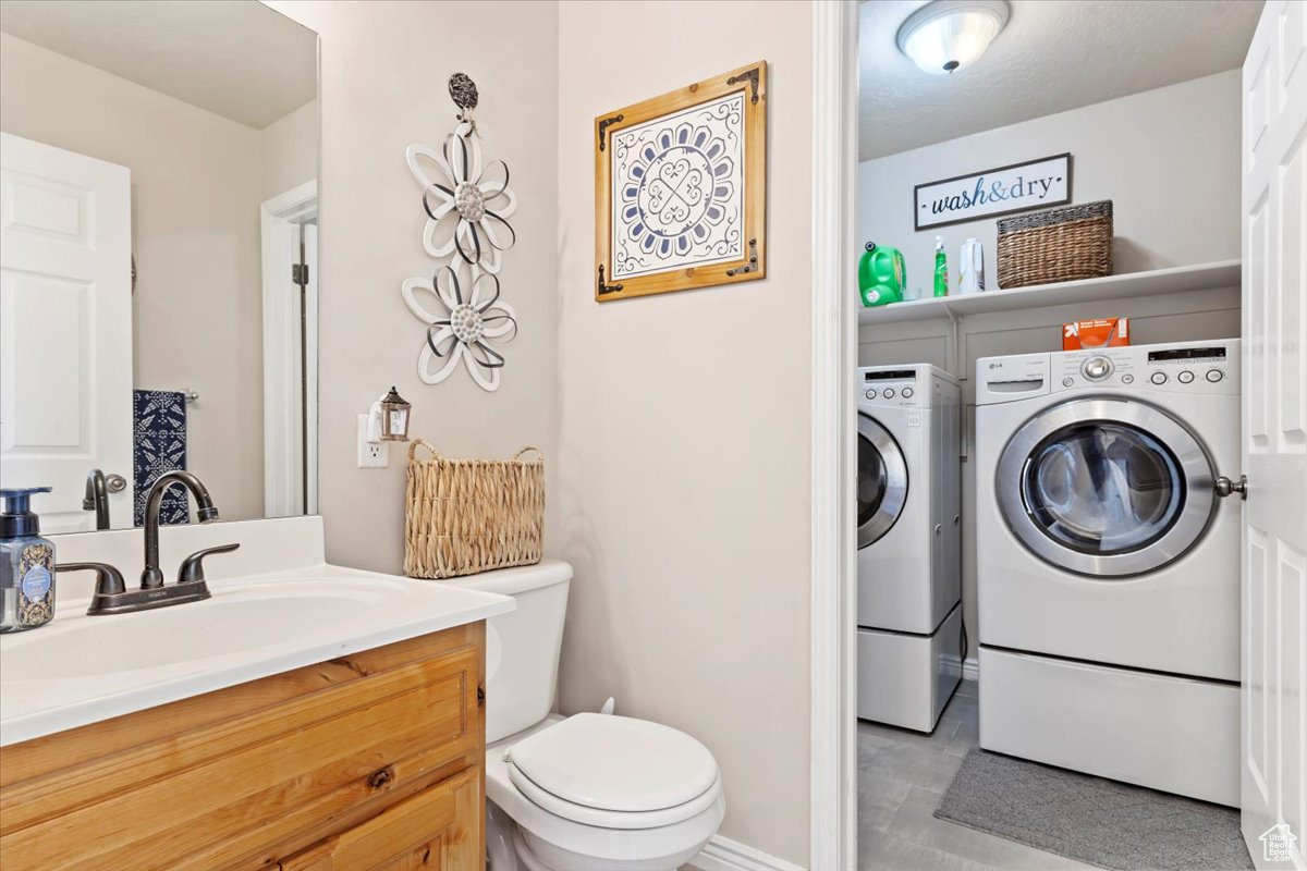 Bathroom with washing machine and clothes dryer, vanity, and toilet