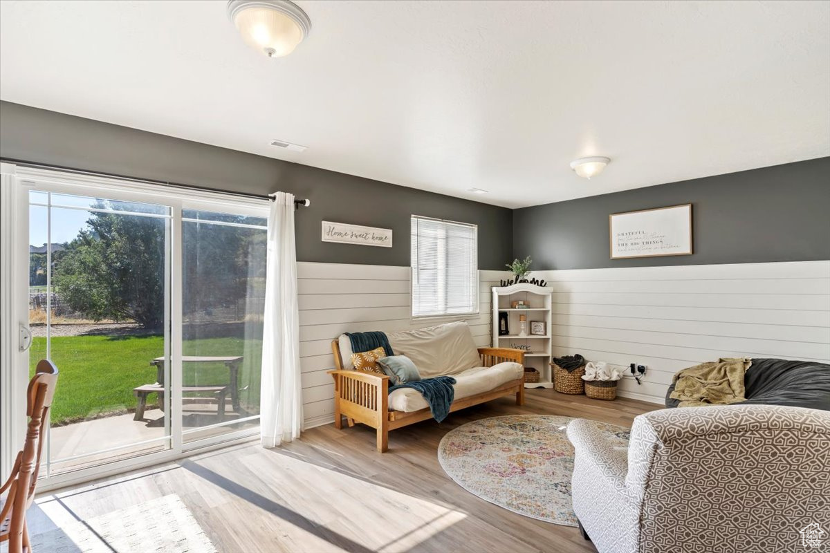 Living room with light hardwood / wood-style floors, wooden walls, and plenty of natural light