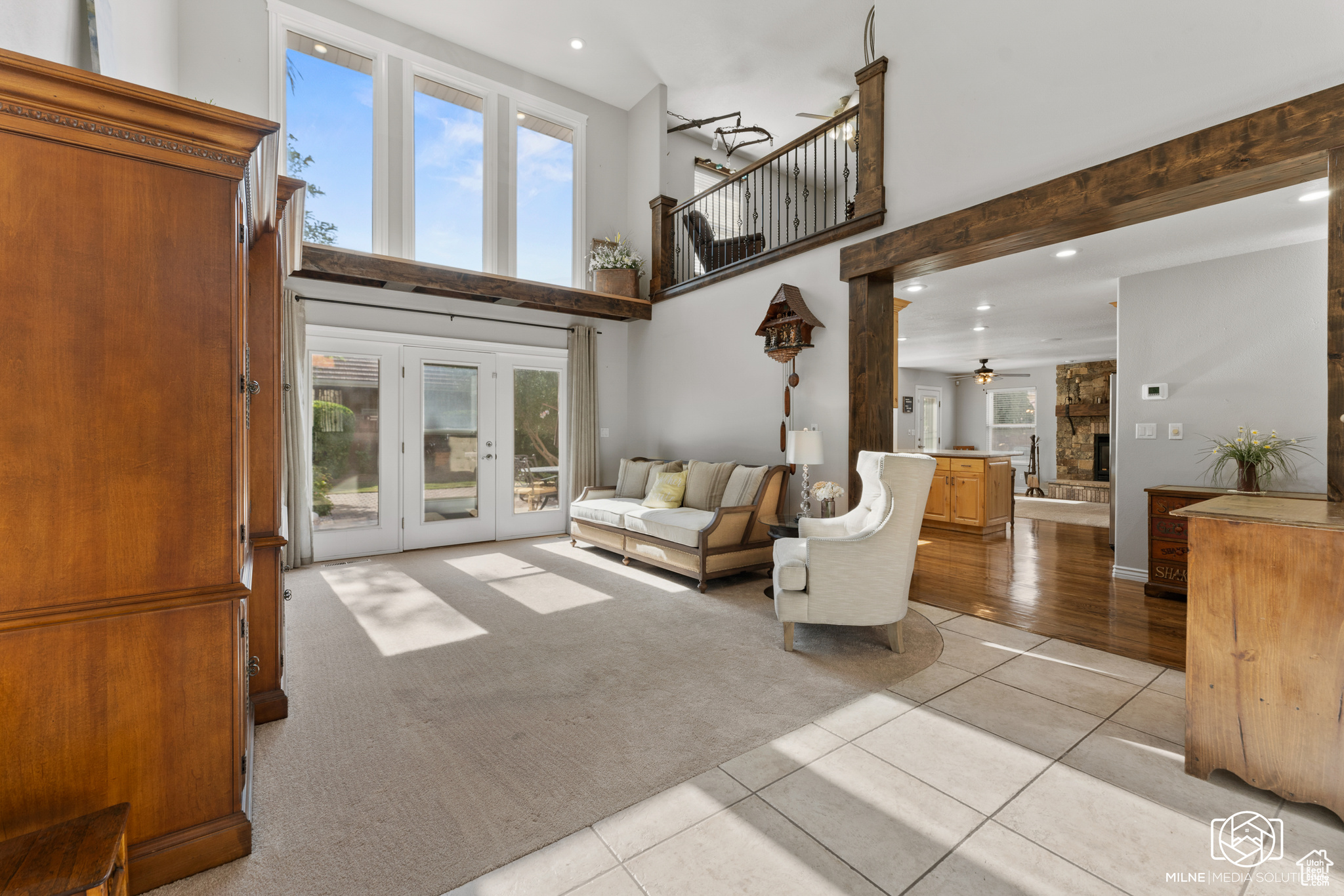 Living room with a high ceiling, ceiling fan, a fireplace, and light tile patterned floors