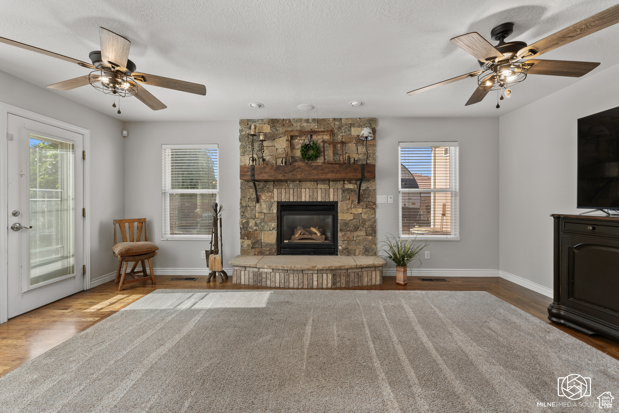 Unfurnished living room featuring a healthy amount of sunlight, a fireplace, and ceiling fan