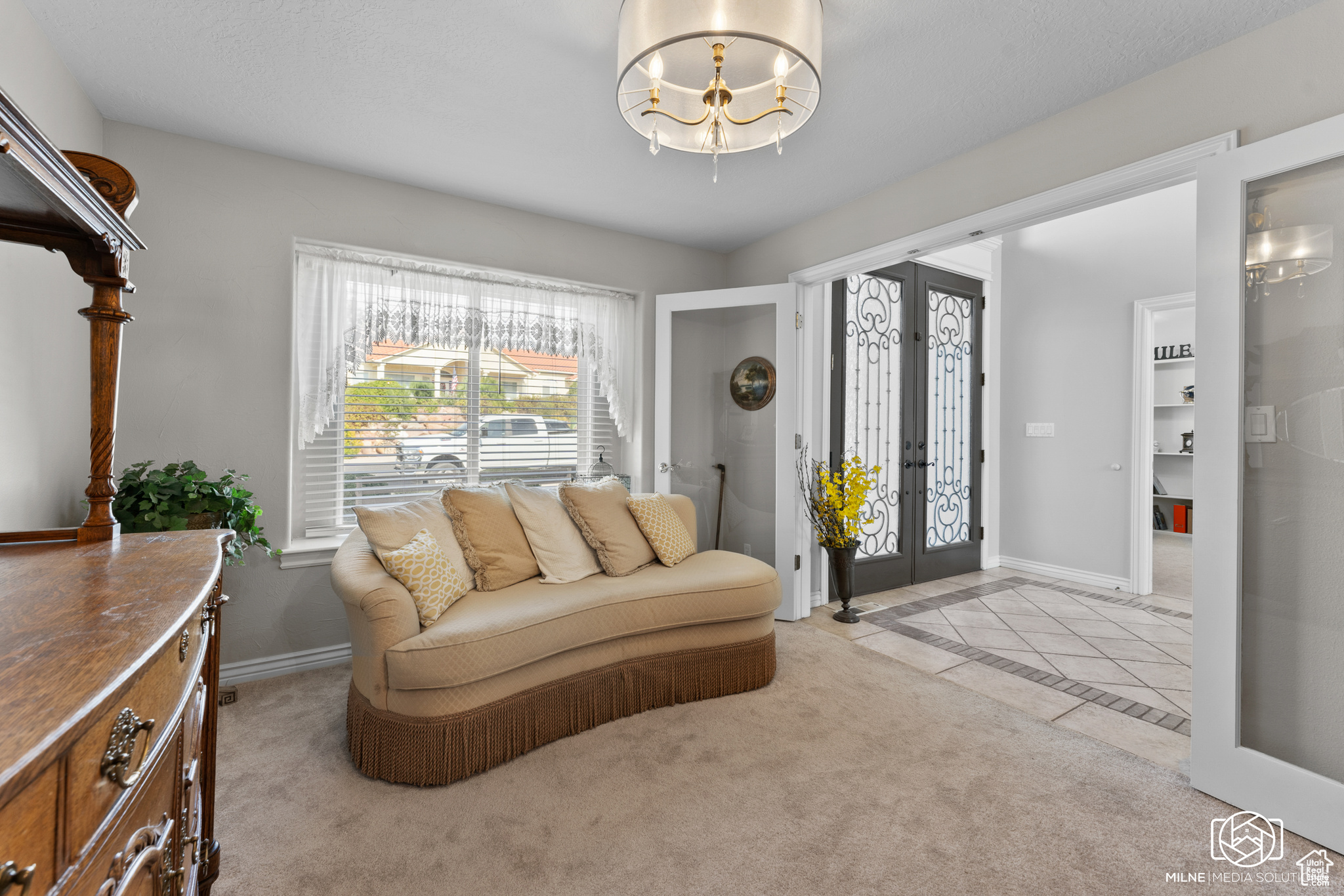 Carpeted living room featuring a chandelier and french doors