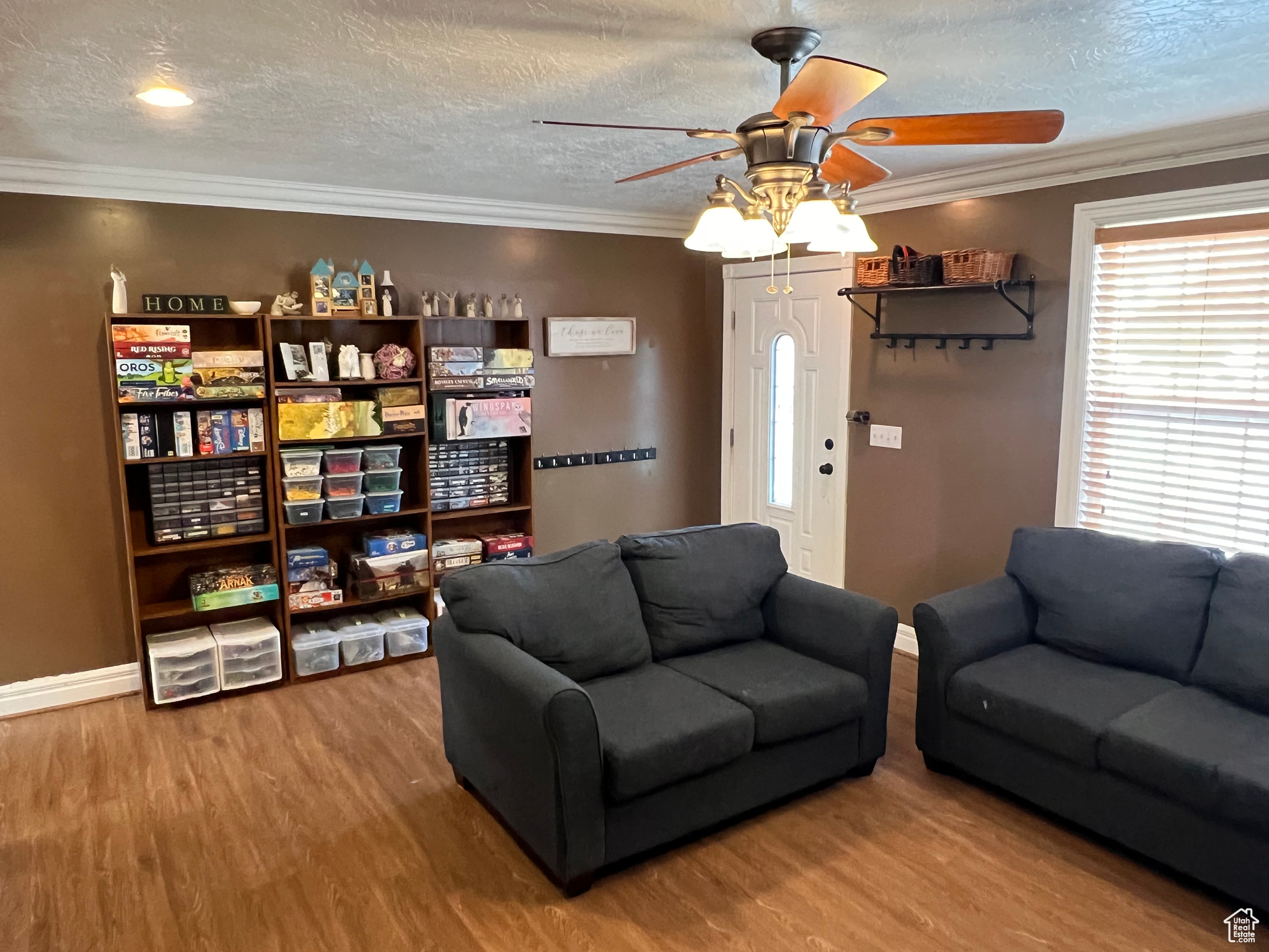 Living room with ceiling fan, a textured ceiling, crown molding, and hardwood / wood-style floors