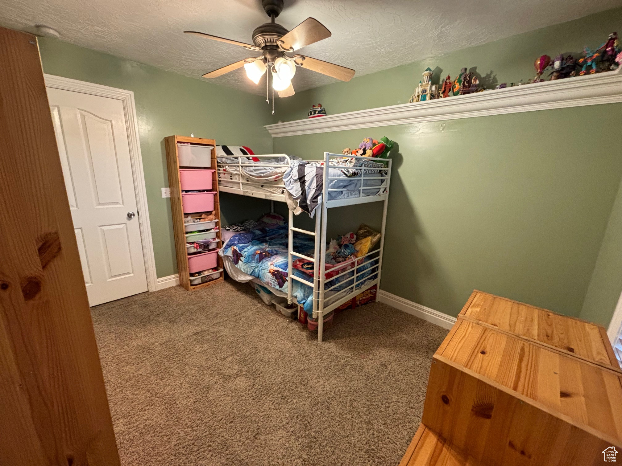 Carpeted bedroom featuring ceiling fan and a textured ceiling