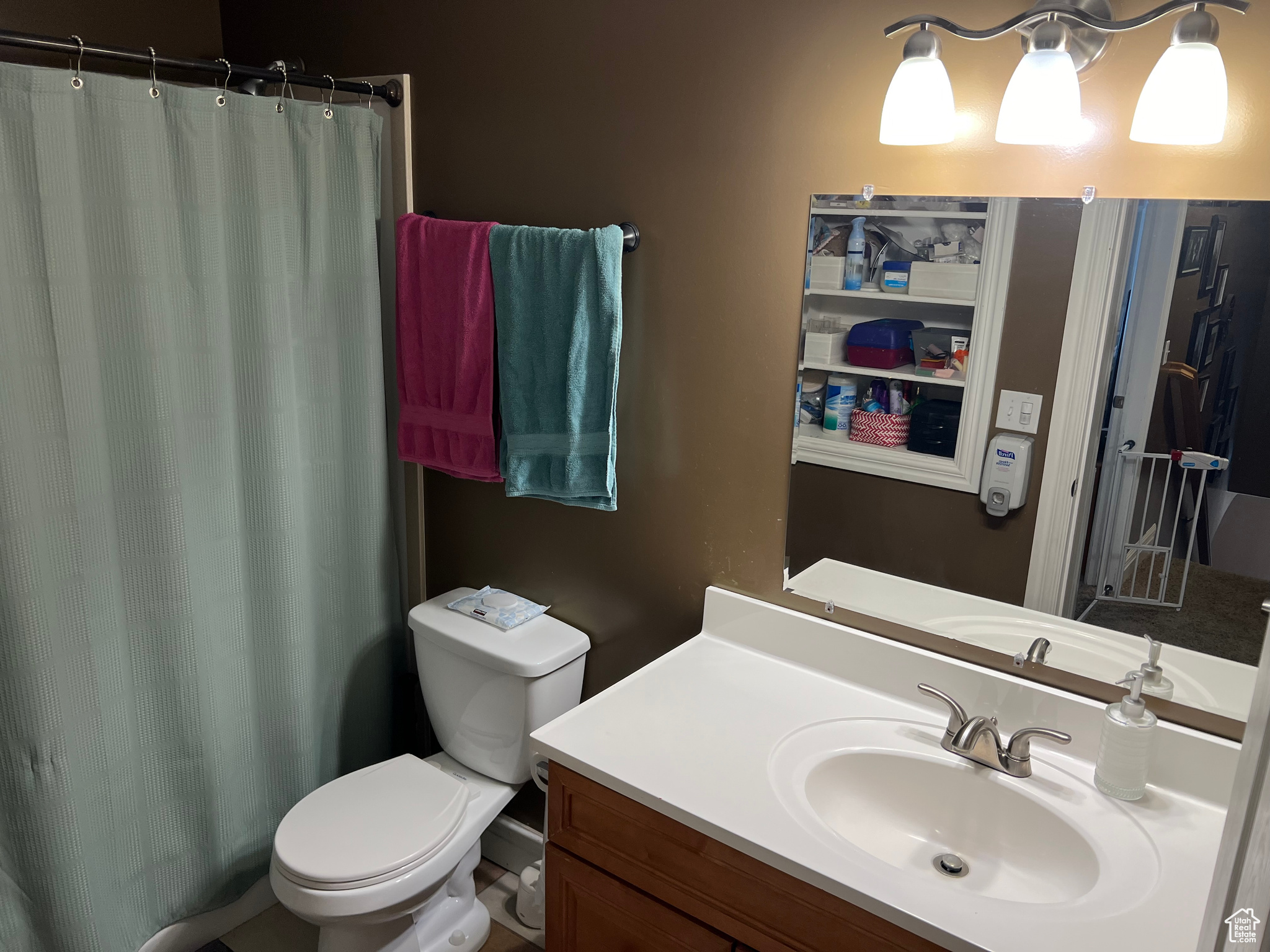 Bathroom with curtained shower, vanity, and toilet