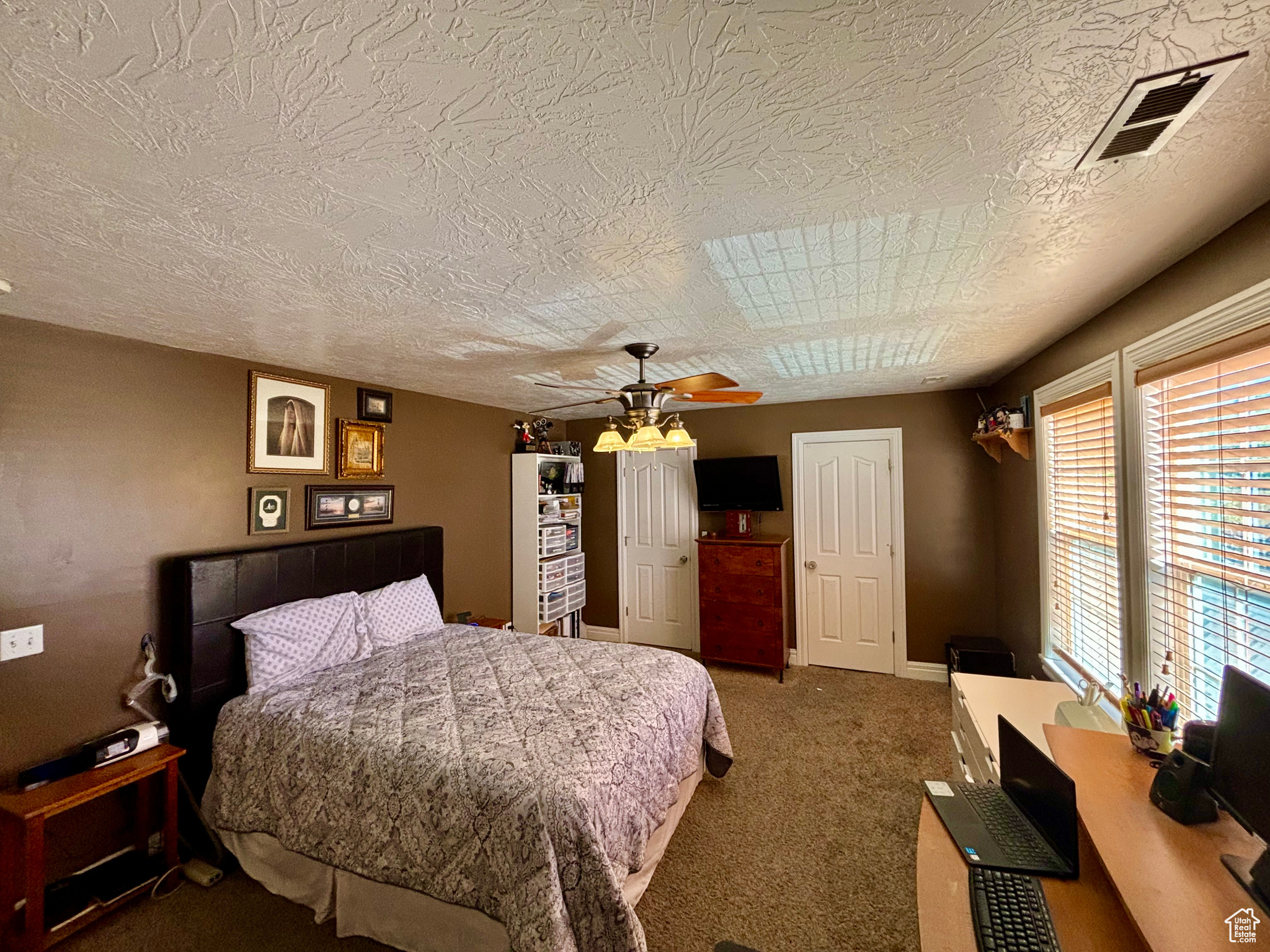 Carpeted bedroom featuring ceiling fan and a textured ceiling