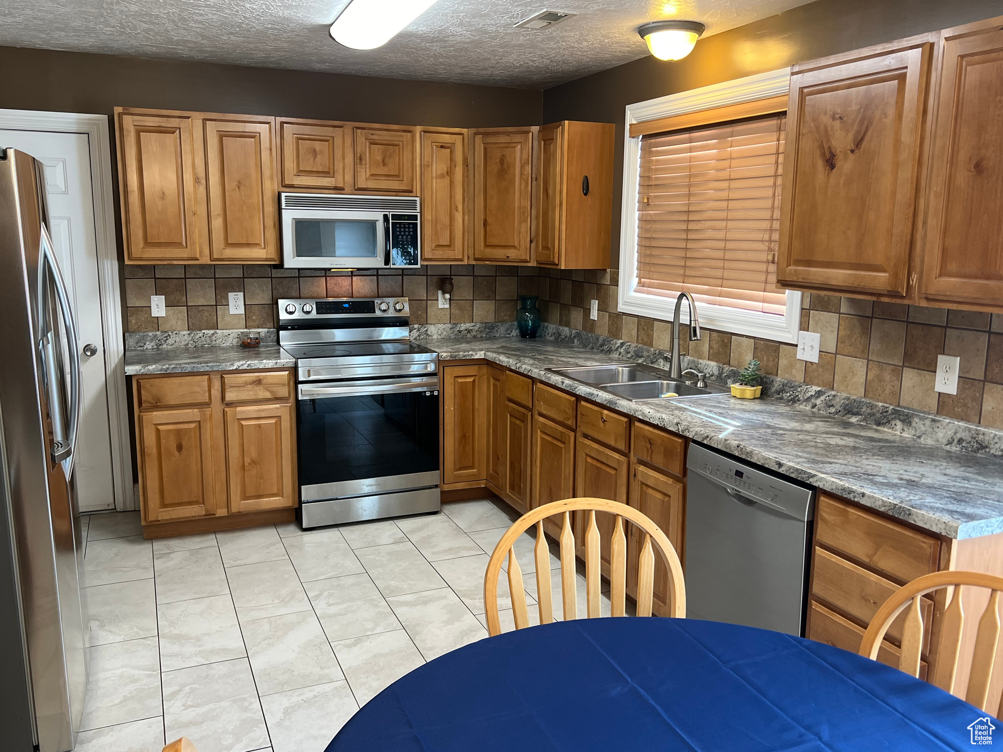 Kitchen featuring a textured ceiling, backsplash, sink, and stainless steel appliances