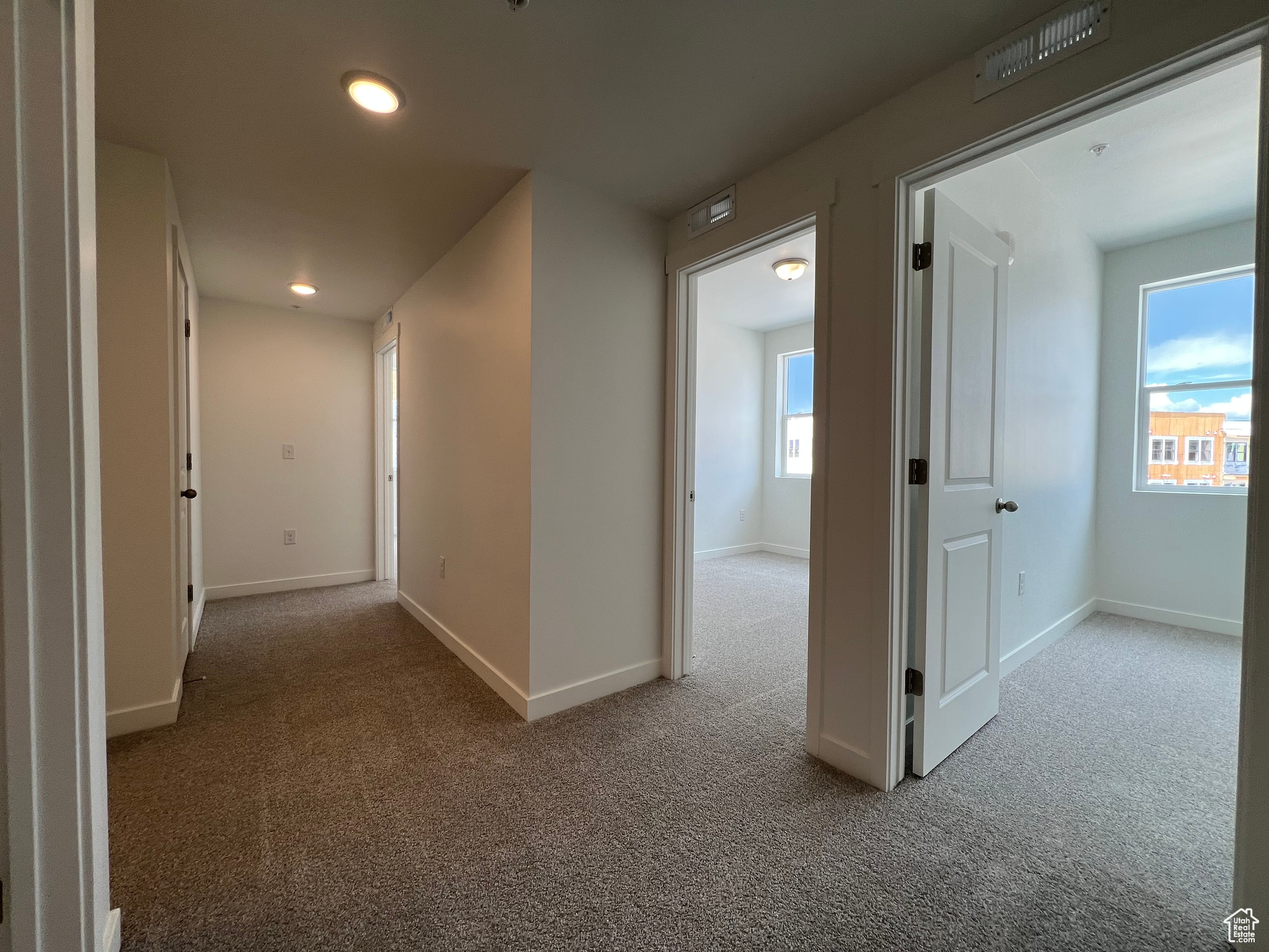 Corridor featuring light colored carpet and a wealth of natural light