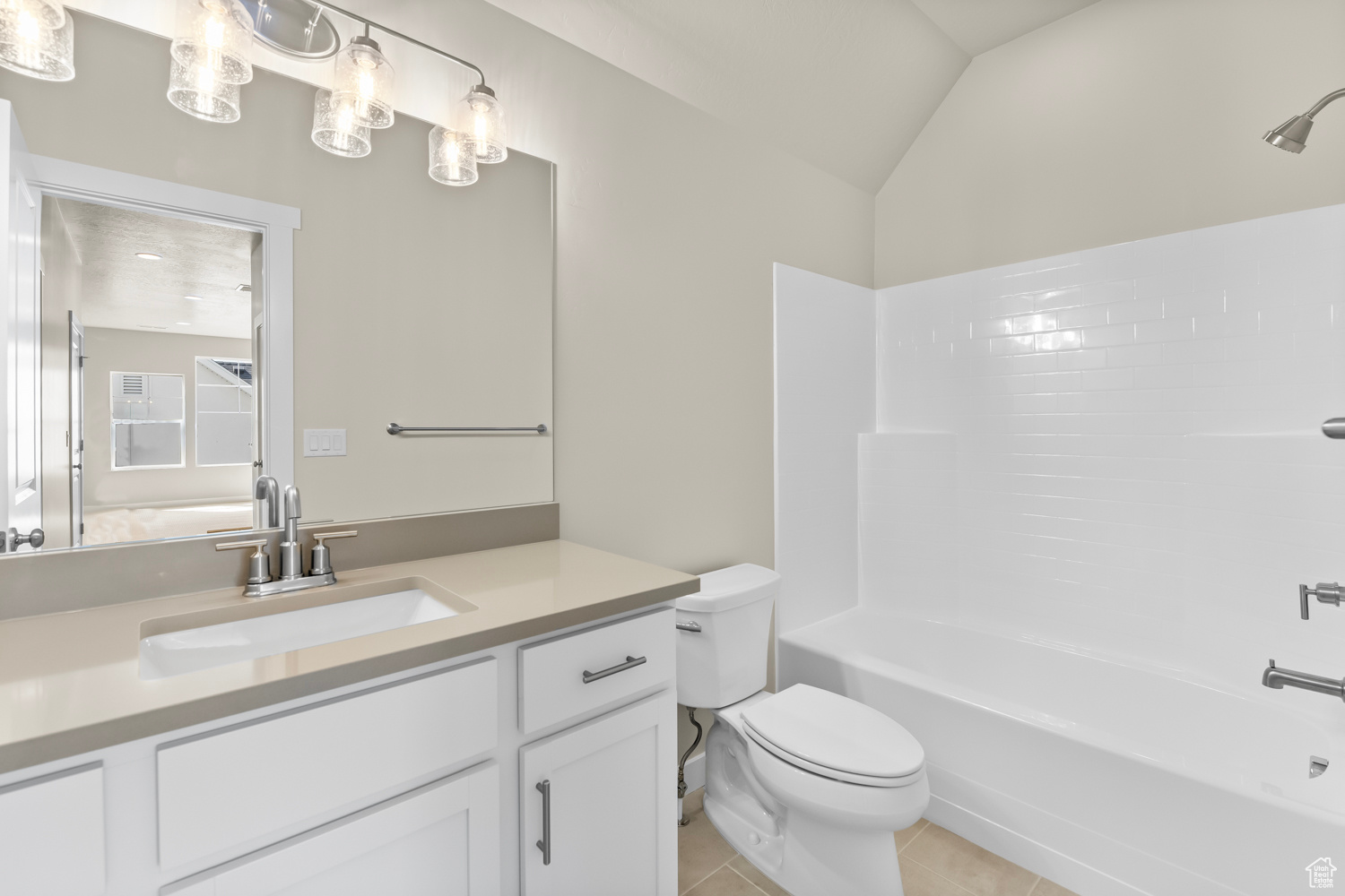 Full bathroom with vanity, shower / bathtub combination, lofted ceiling, tile patterned flooring, and toilet