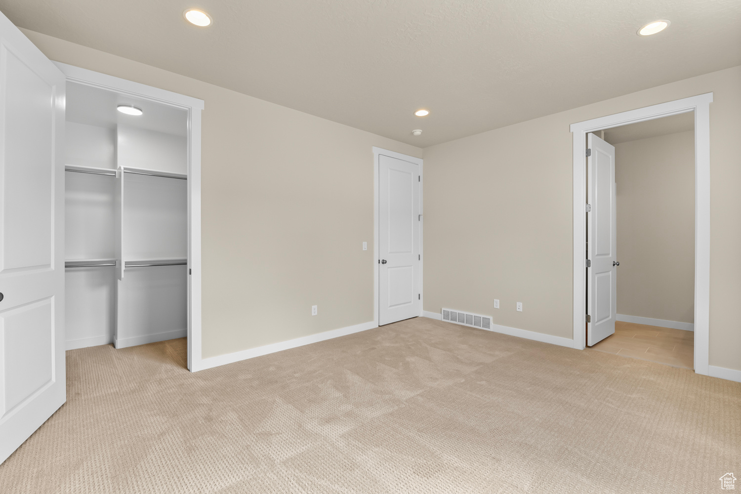 Unfurnished bedroom featuring light carpet and a closet