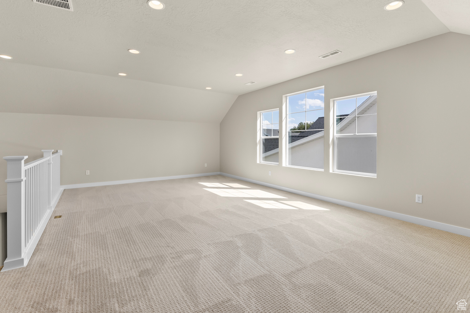 Additional living space with vaulted ceiling and light colored carpet