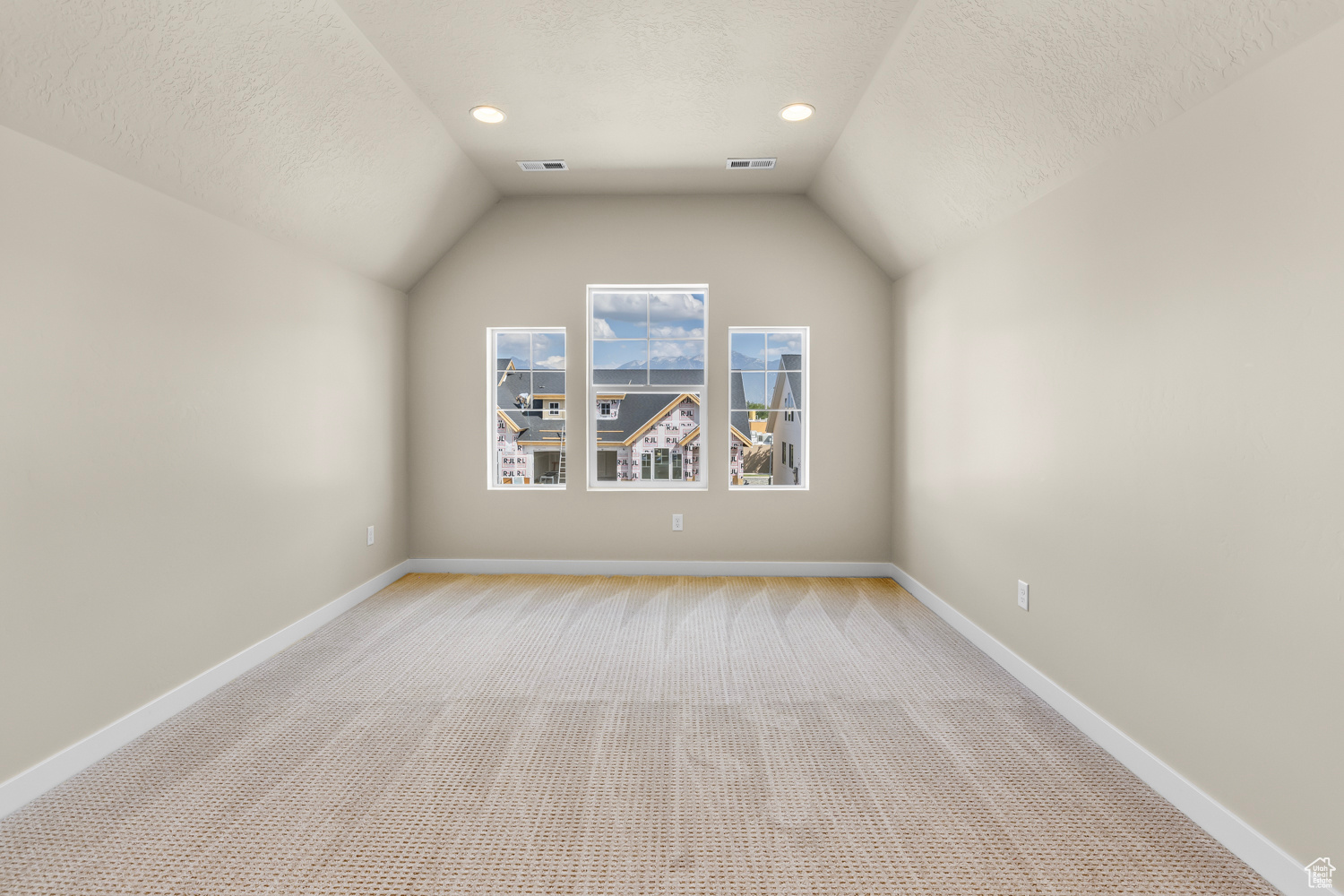 Unfurnished room with a textured ceiling, lofted ceiling, and light carpet