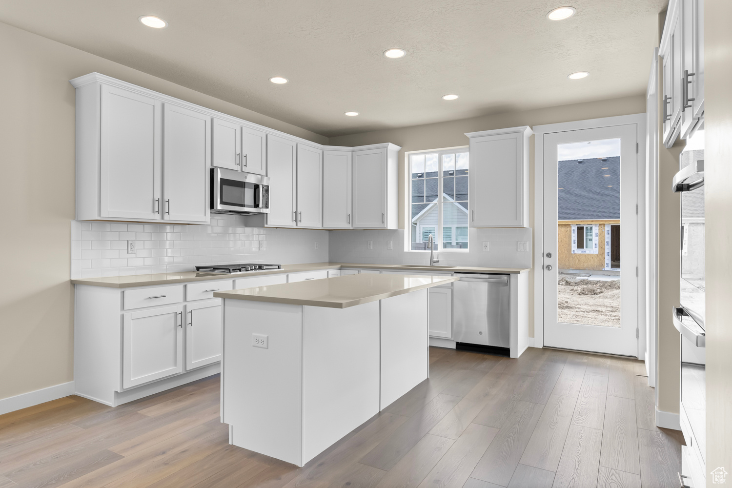 Kitchen featuring stainless steel appliances, white cabinets, a center island, and hardwood / wood-style flooring