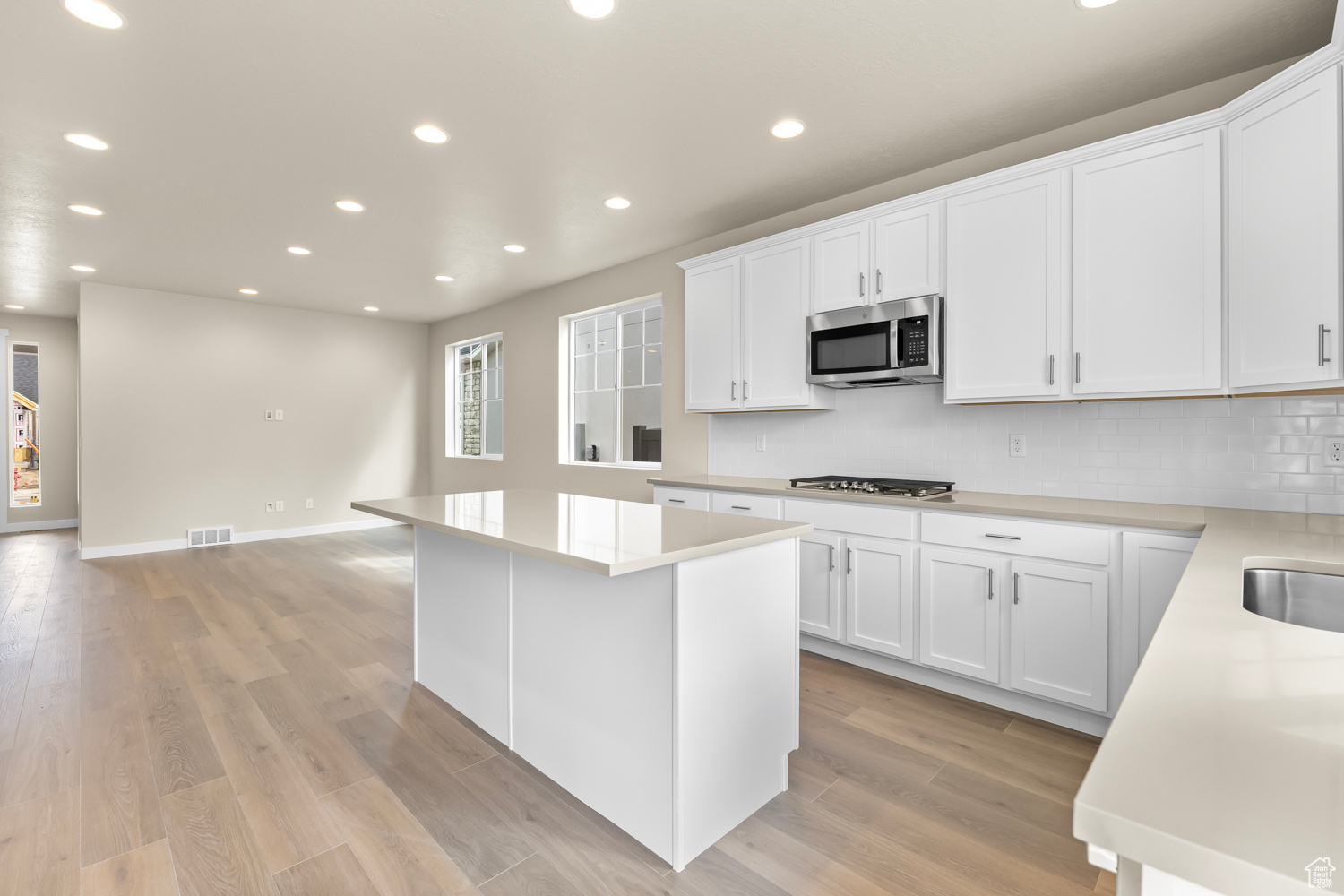 Kitchen featuring appliances with stainless steel finishes, a center island, light hardwood / wood-style flooring, and white cabinets