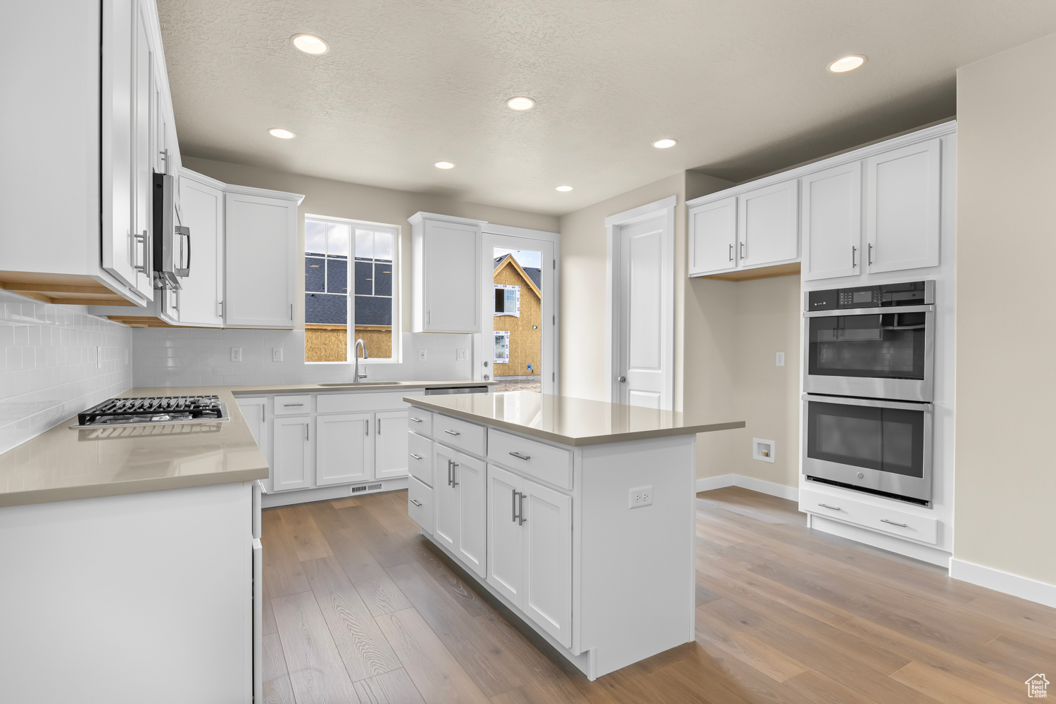 Kitchen featuring appliances with stainless steel finishes, light hardwood / wood-style floors, a kitchen island, and white cabinetry