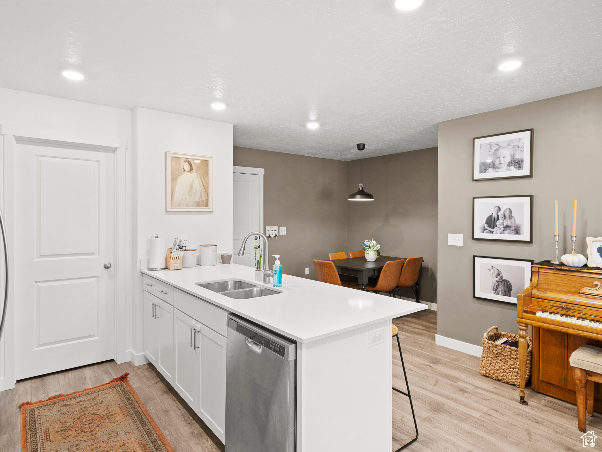 Kitchen with pendant lighting, dishwasher, sink, light hardwood / wood-style flooring, and a kitchen breakfast bar