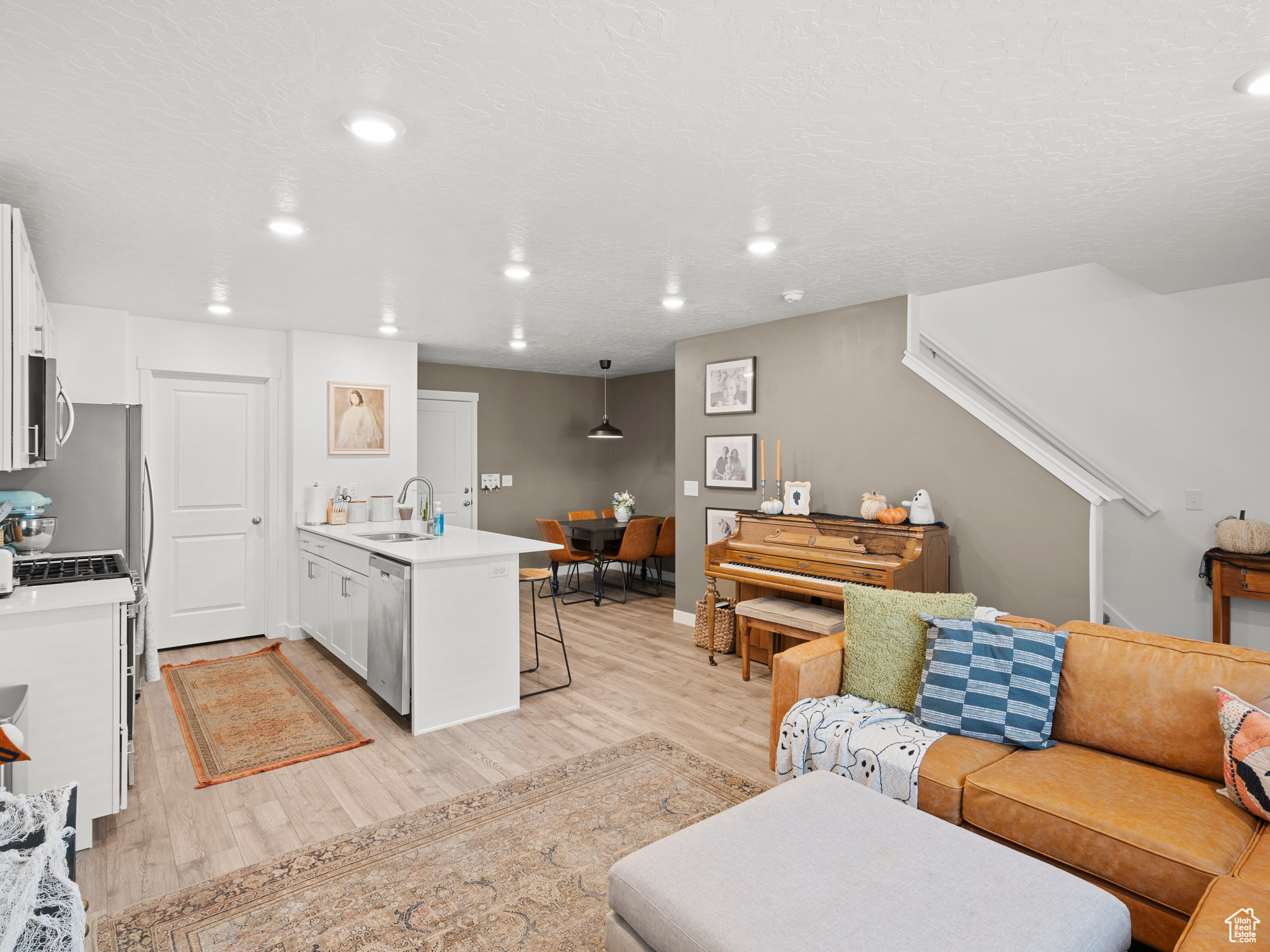 Kitchen featuring decorative light fixtures, white cabinetry, appliances with stainless steel finishes, a breakfast bar, and light wood-type flooring