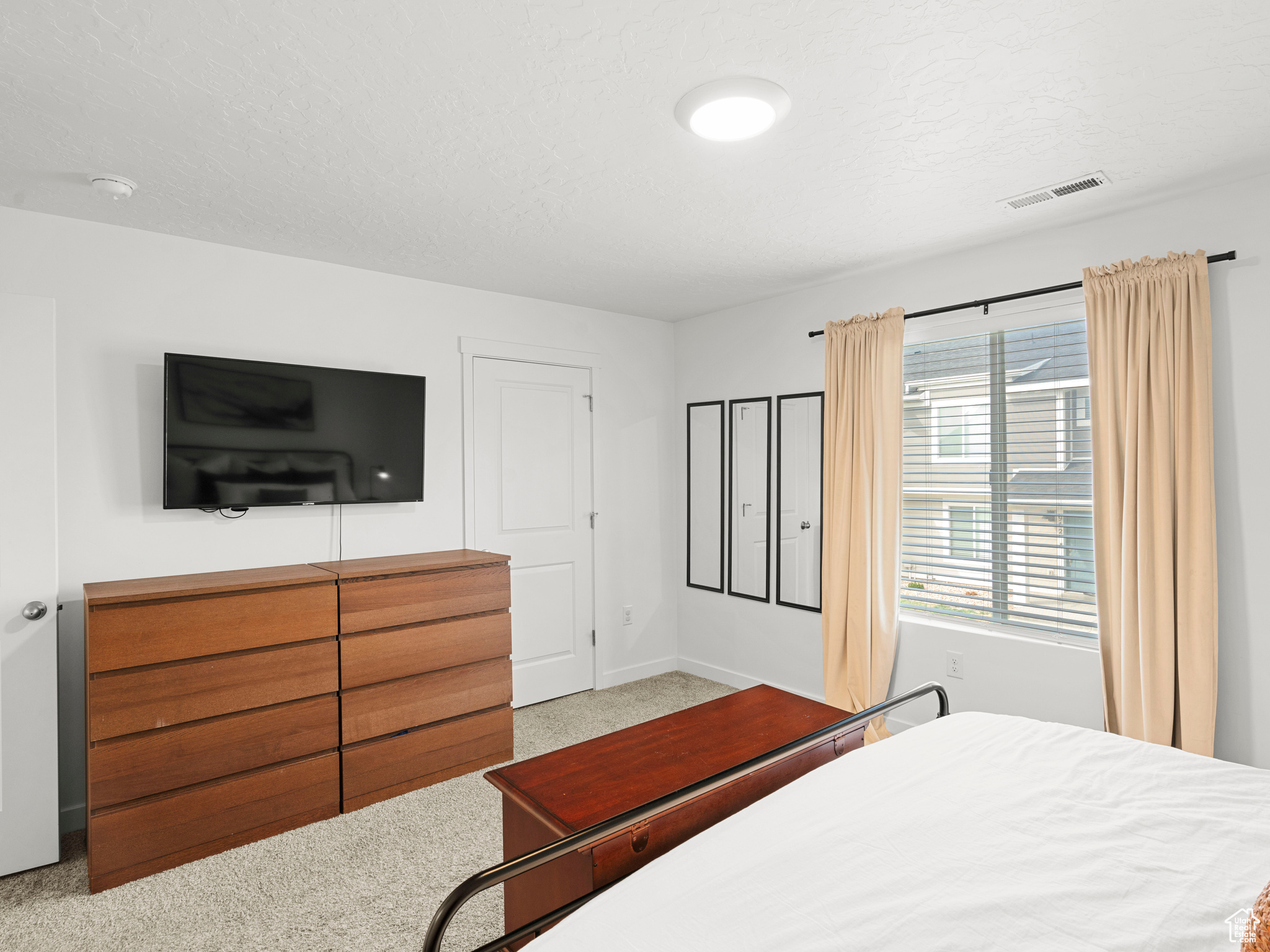 Bedroom with a textured ceiling and light colored carpet