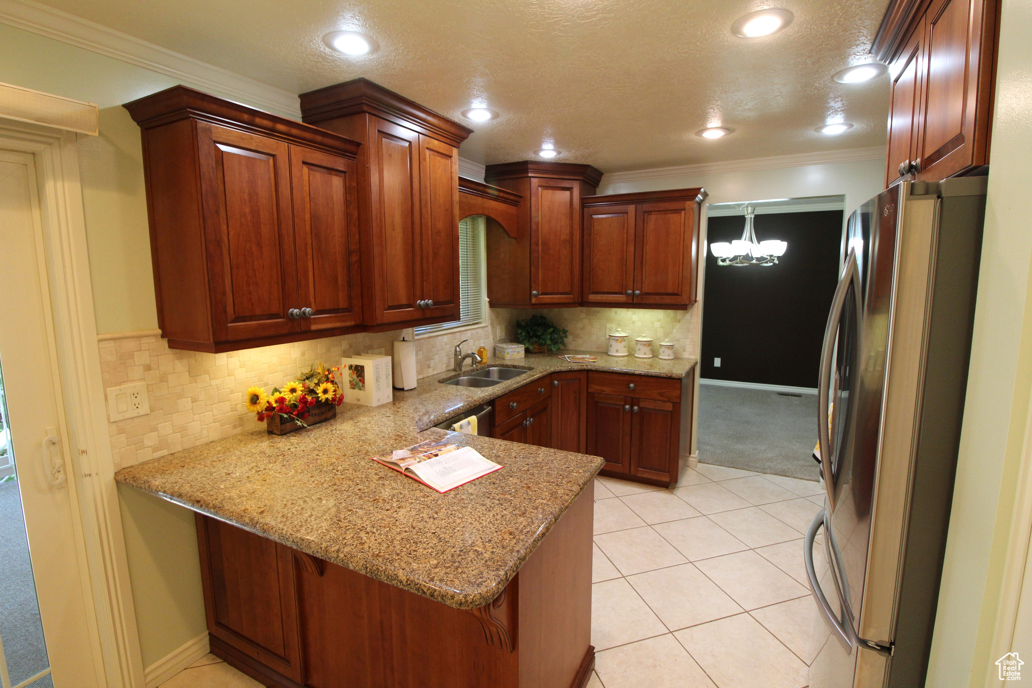 Kitchen with light tile patterned floors, sink, crown molding, kitchen bar, and plenty of cabinets