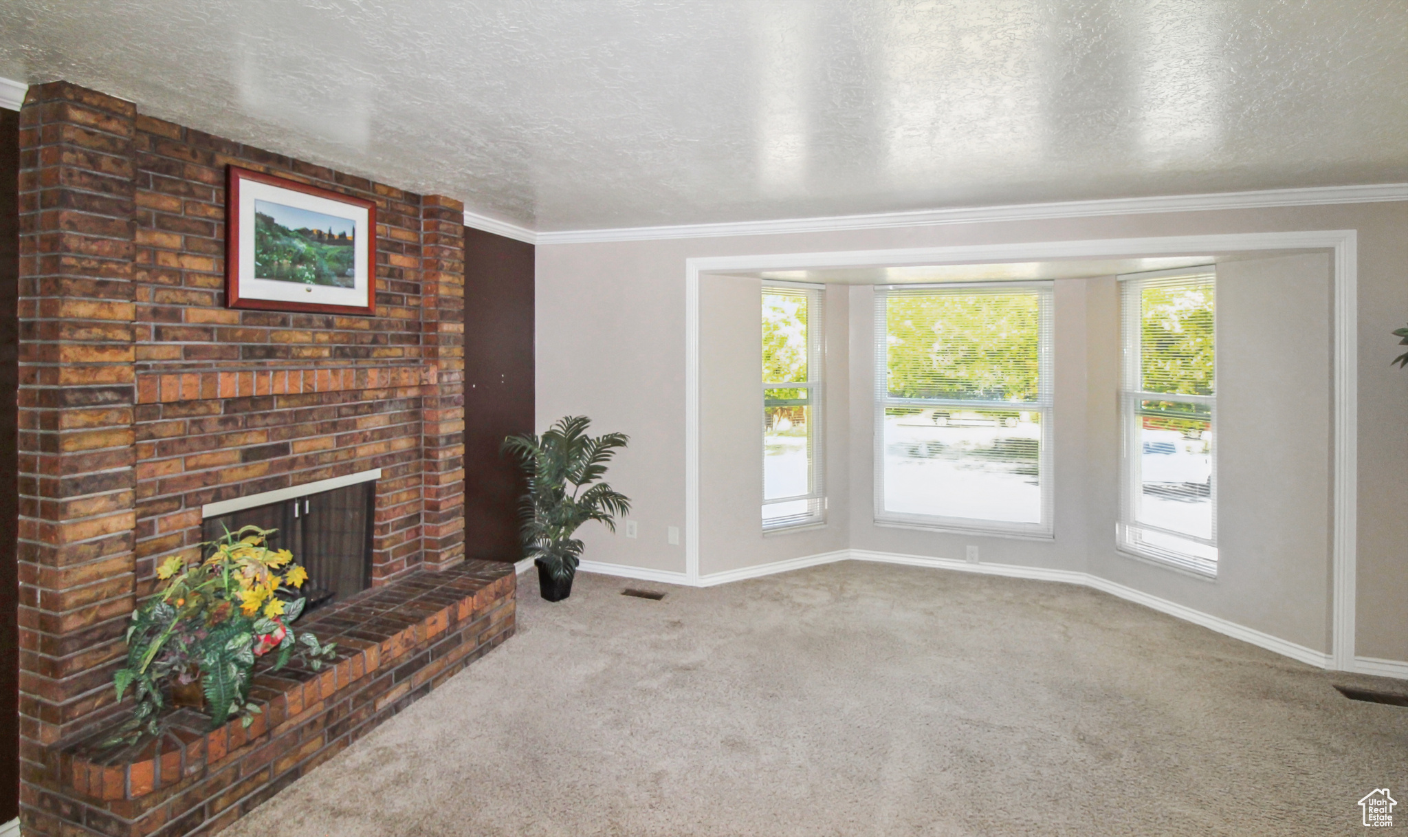 Spacious living room featuring a brick fireplace, bay window, and crown molding