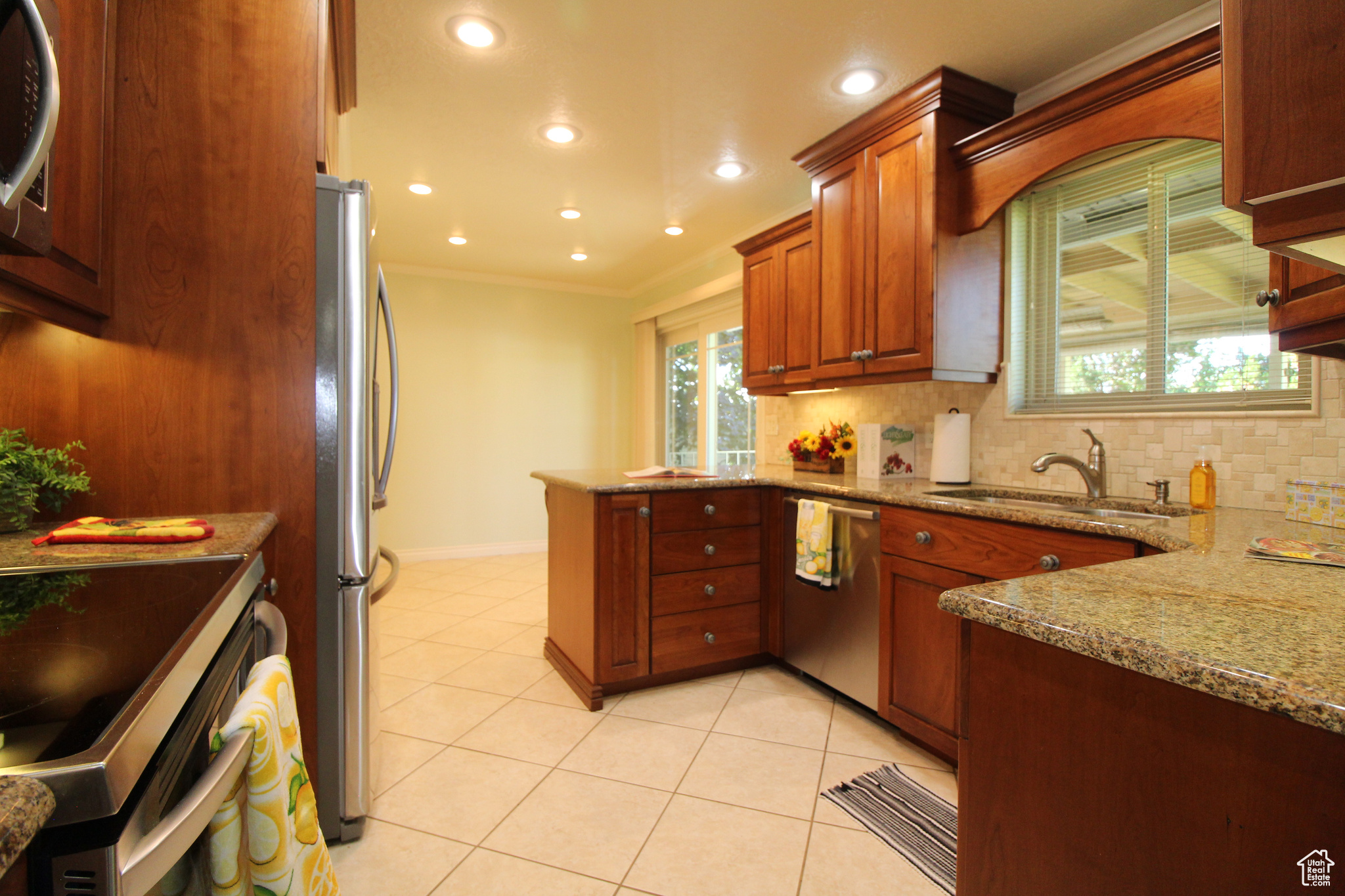 Kitchen with light tile patterned floors, sink, crown molding, kitchen bar, and plenty of cabinets