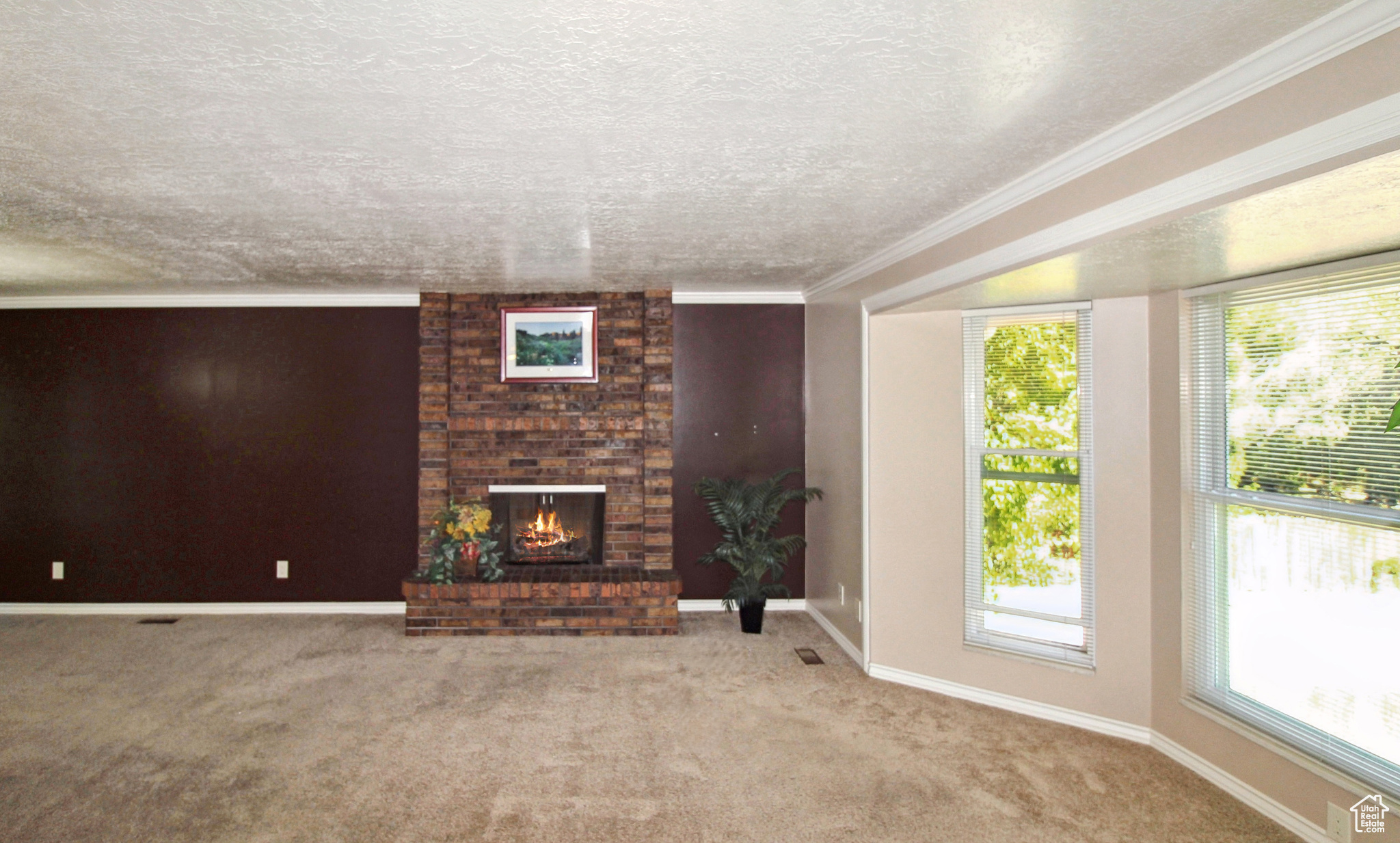 Spacious living room featuring a brick fireplace, bay window, and crown molding