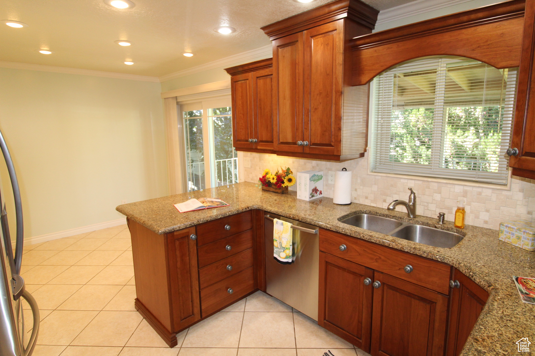 Kitchen with light tile patterned floors, sink, crown molding, kitchen bar, and plenty of cabinets