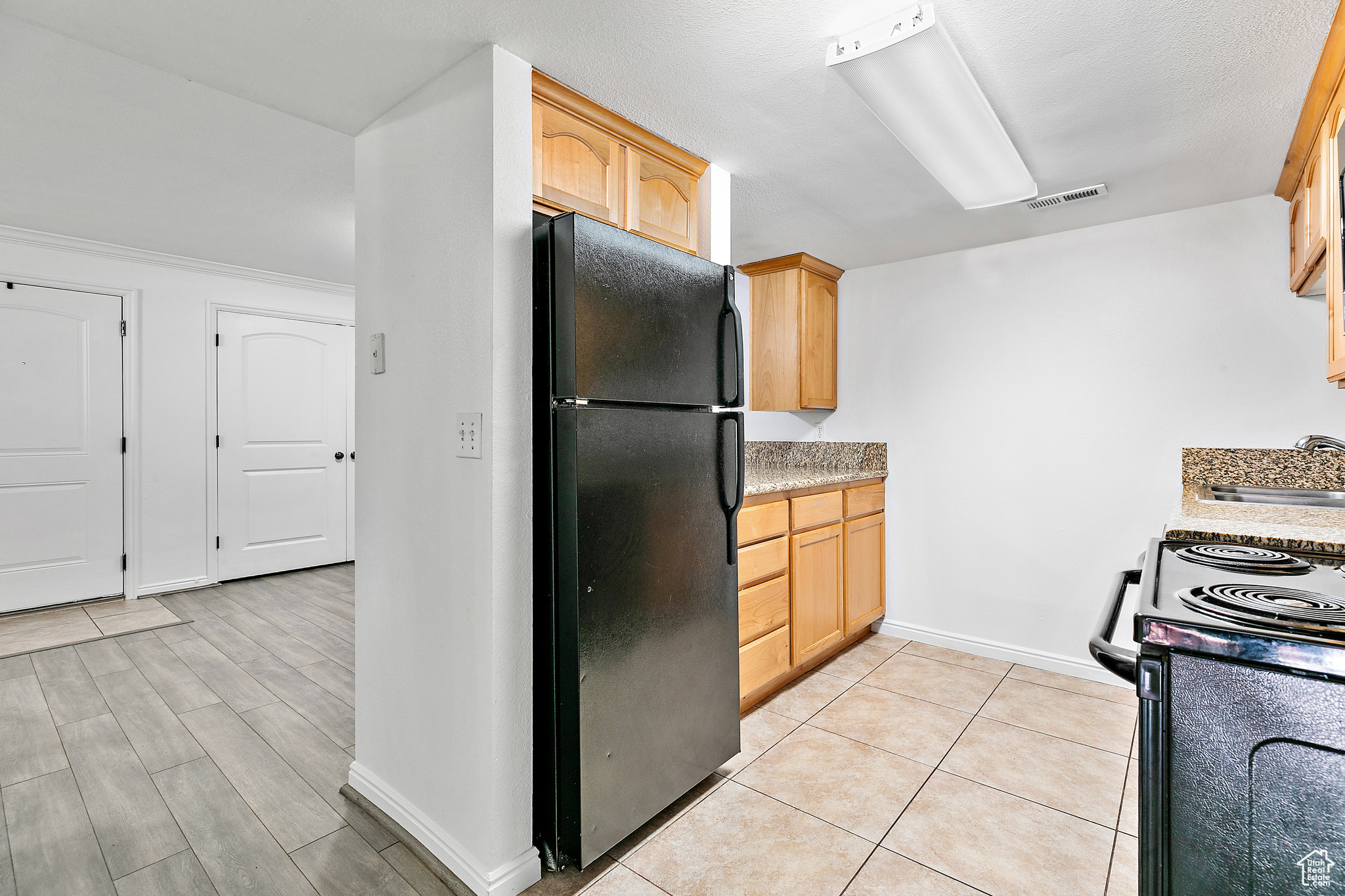 Kitchen featuring light brown cabinetry, sink, and black appliances / Included Refrigerator