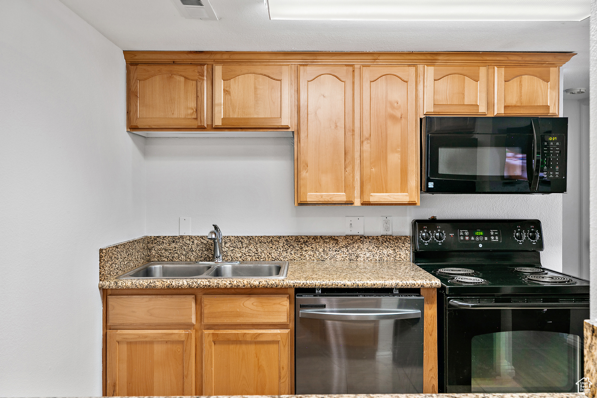 Kitchen featuring light brown cabinetry, sink, and black appliances / Included Refrigerator