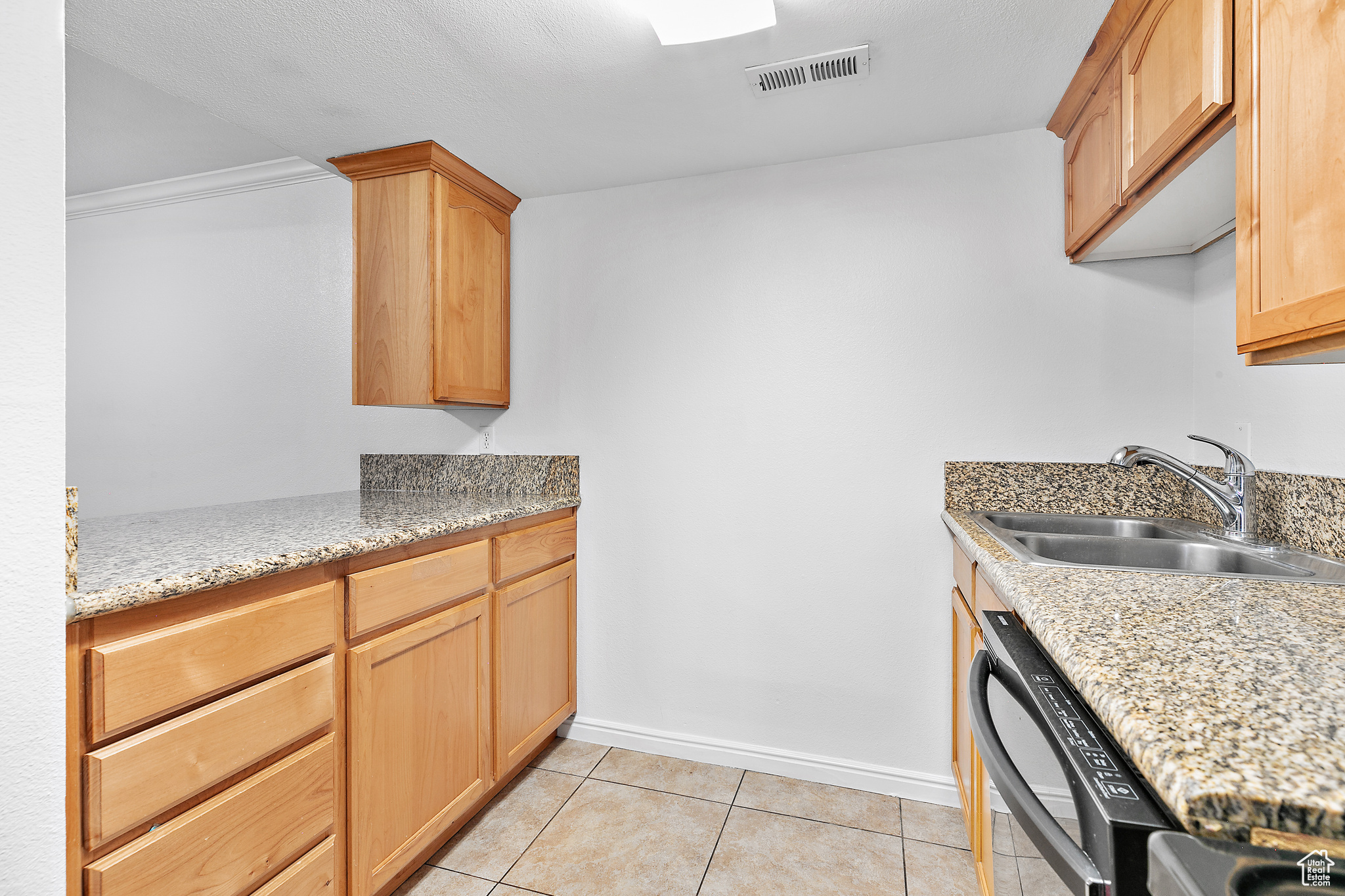 Kitchen featuring light brown cabinetry, sink, and black appliances / Included Refrigerator