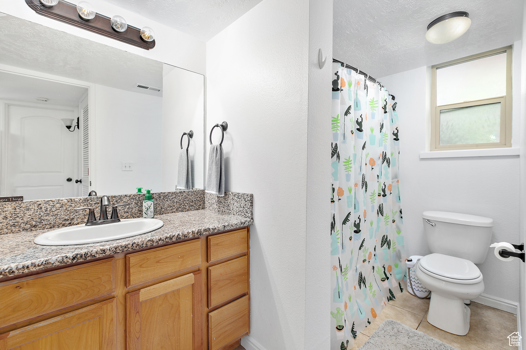 Bathroom featuring vanity, toilet, a textured ceiling, and tile patterned floors